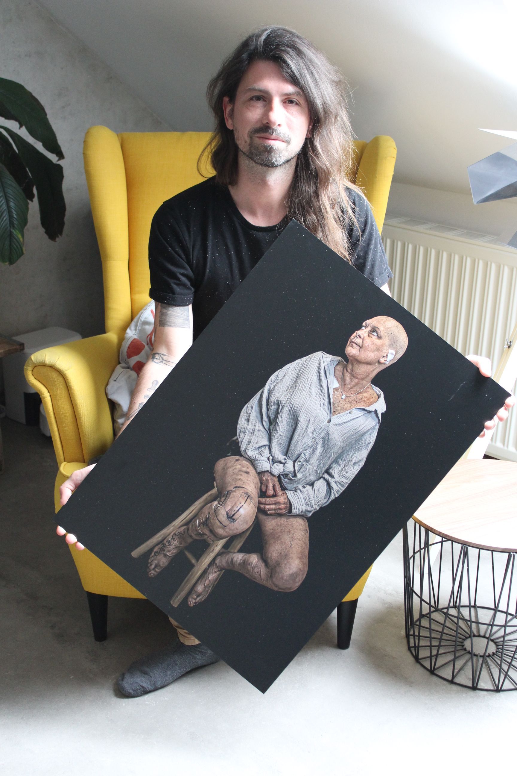 Das Foto zeigt einen Mann, der eine große Fotografie hält.