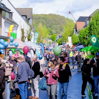 Viele Menschen laufen an Ständen eines Straßenfests vorbei.