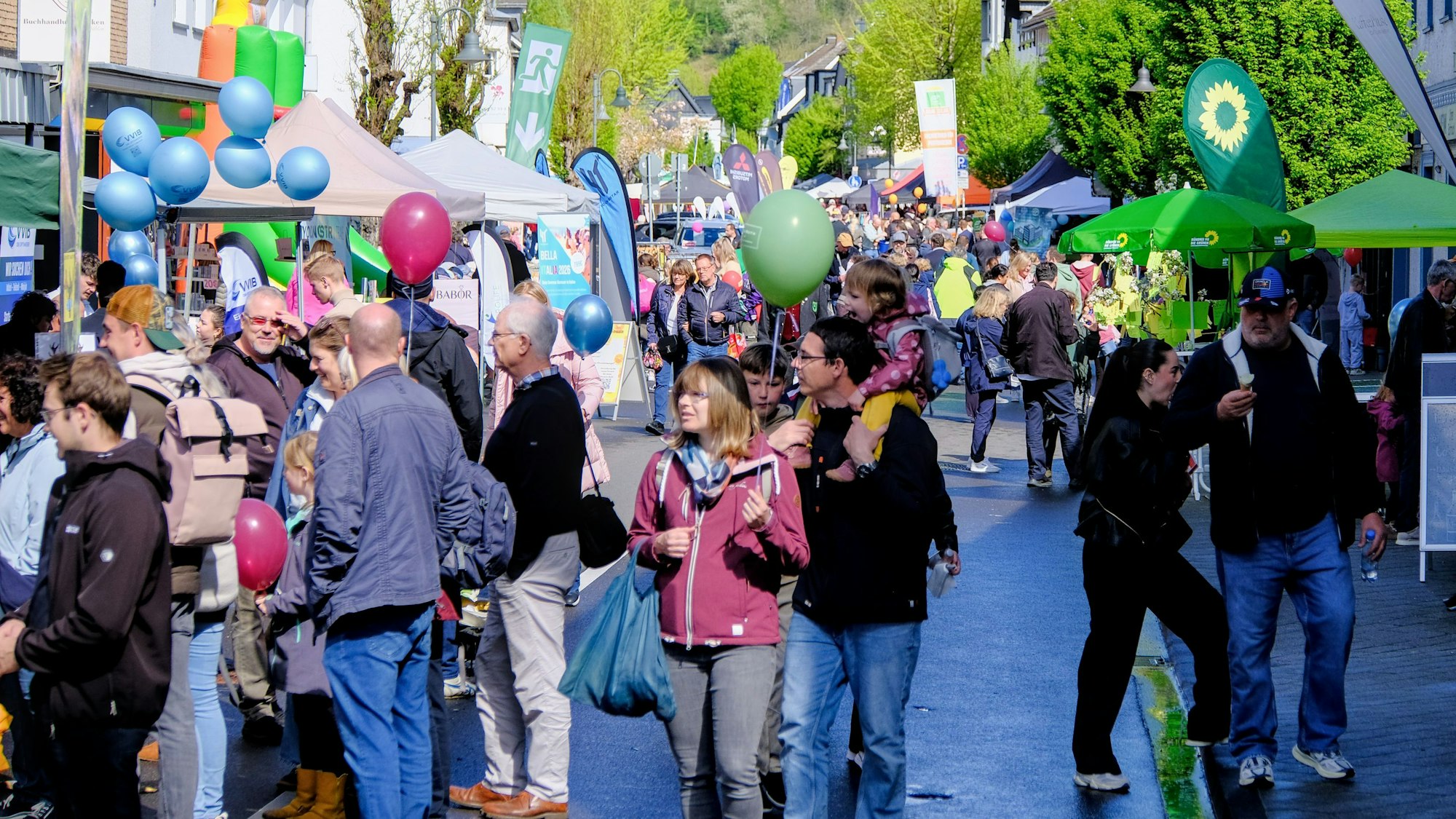 Viele Menschen laufen an Ständen eines Straßenfests vorbei.