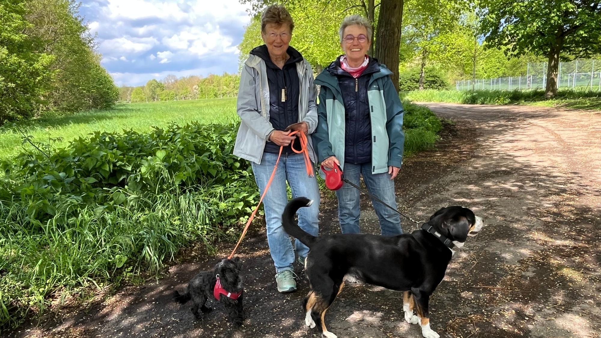Zwei Frauen stehen mit zwei Hunden auf einem Weg.