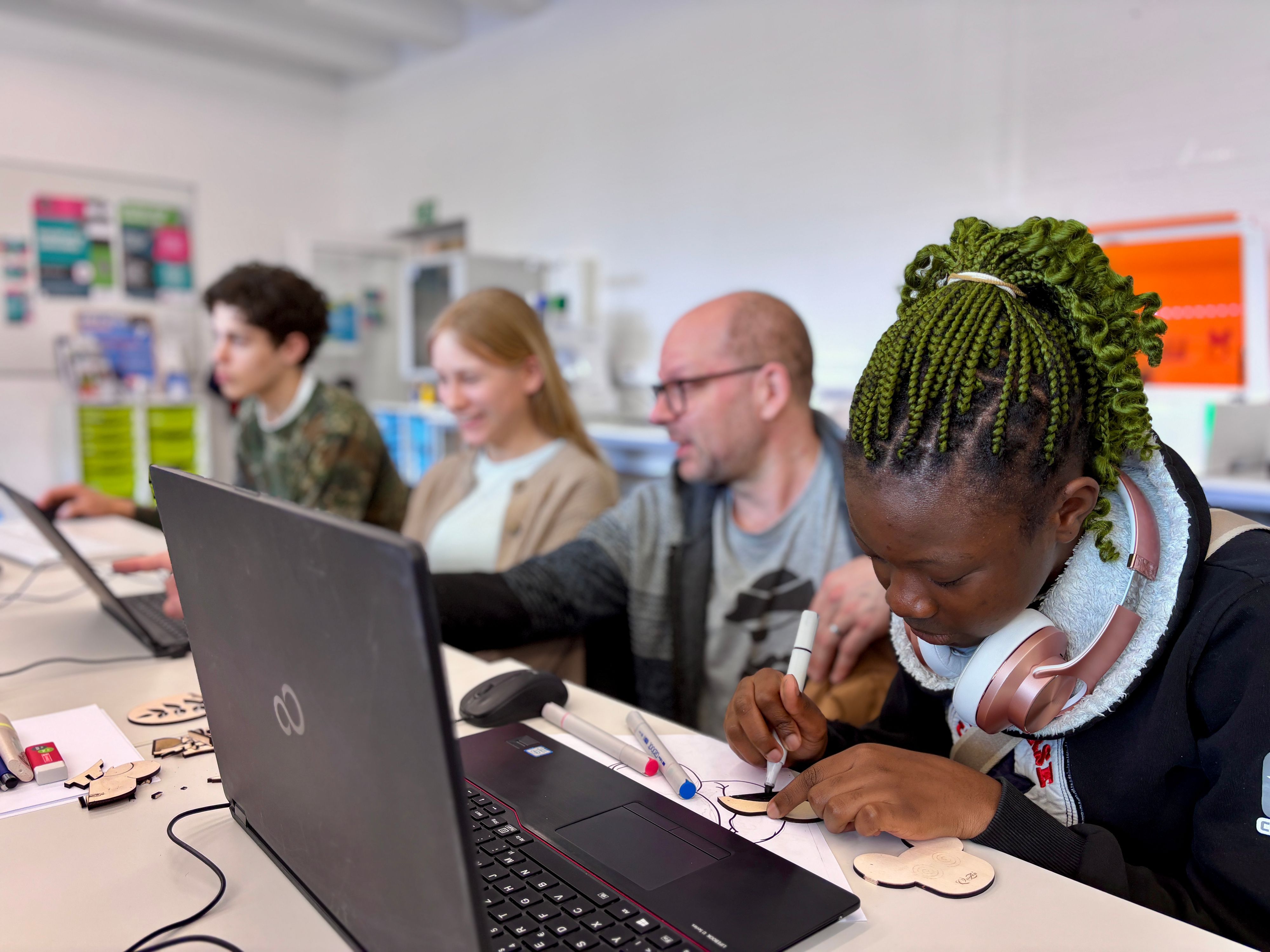 Eine Jugendliche gestaltet ein Logo auf einem Blatt Papier mit Markern.