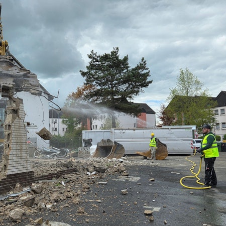 Während der Bagger zubeißt und Mauerreste der alten Markthalle in Waldbröl wegknabbert, sorgt Jens Willkomm mit Wasser dafür, dass der Abbruch der Brandruine nicht zu viel Staub aufwirbelt.