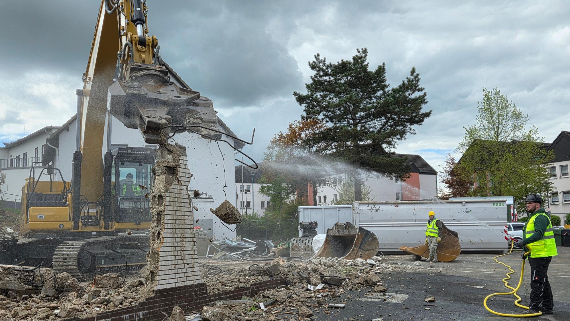Während der Bagger zubeißt und Mauerreste der alten Markthalle in Waldbröl wegknabbert, sorgt Jens Willkomm mit Wasser dafür, dass der Abbruch der Brandruine nicht zu viel Staub aufwirbelt.