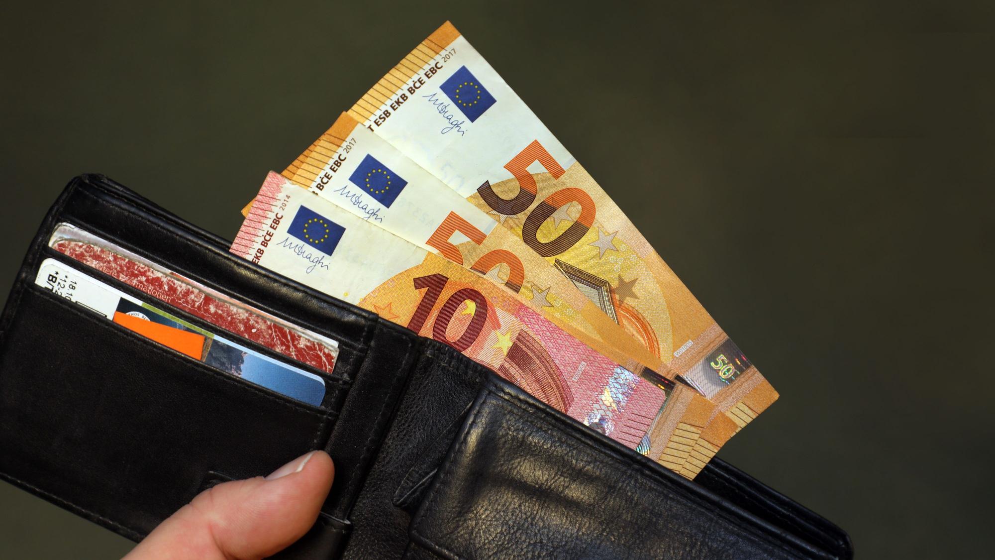 Eine schwarze Geldbörse mit 110 Euro Geldscheinen, die herausschauen.