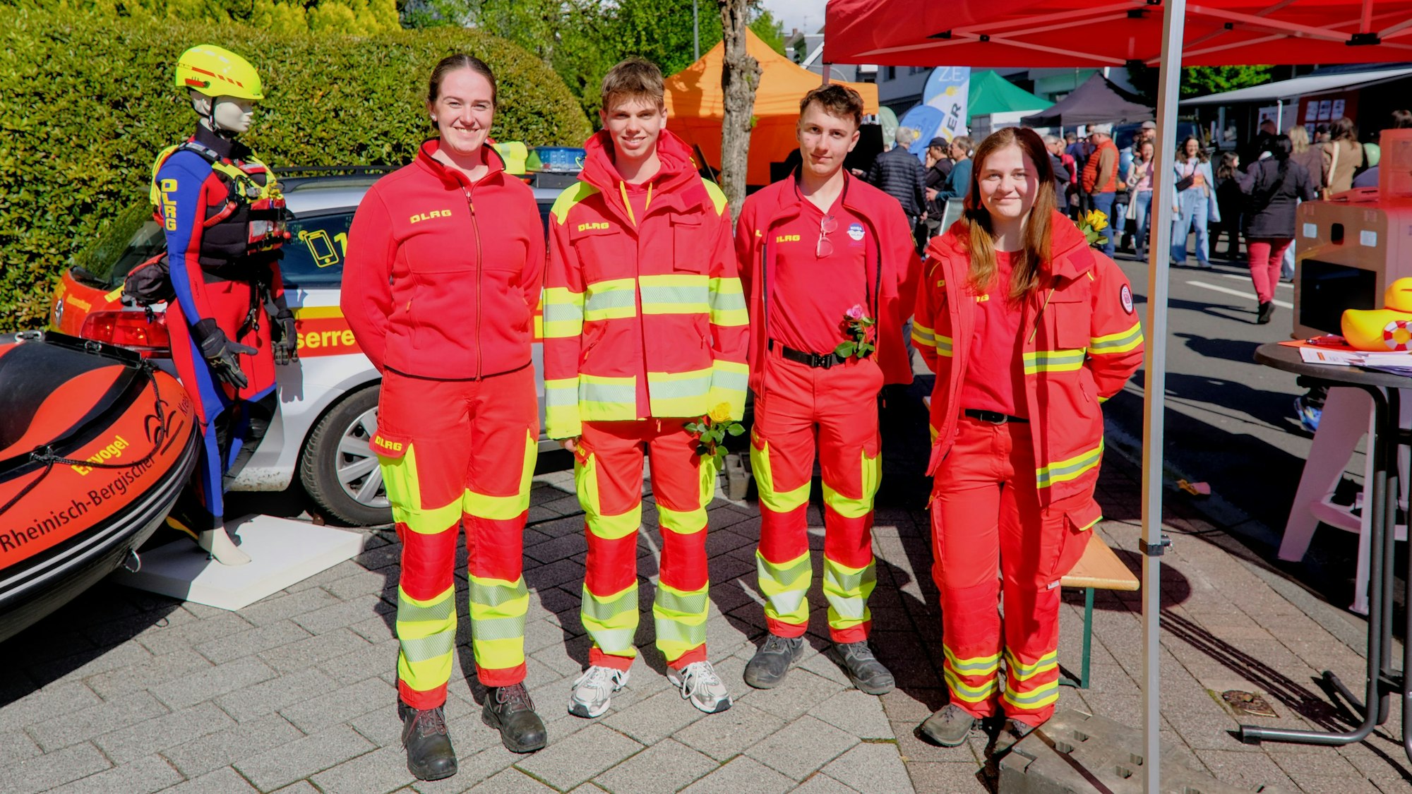 Vier junge Menschen vom DLRG in roter Kleidung lächeln in die Kamera.