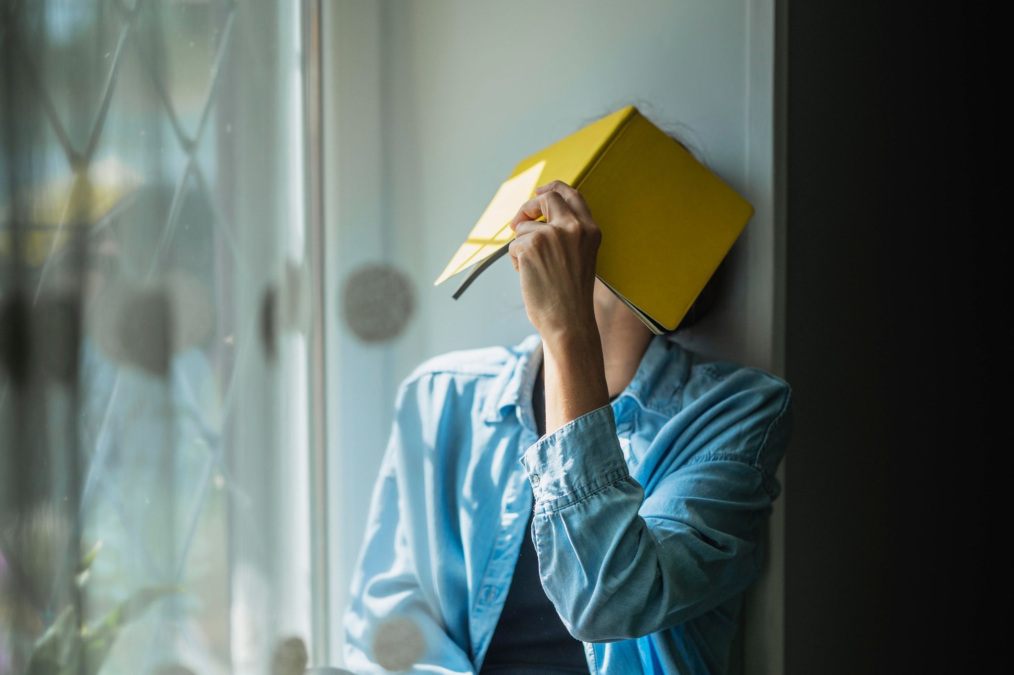 Eine Frau verbirgt ihr Gesicht hinter einem Notizheft