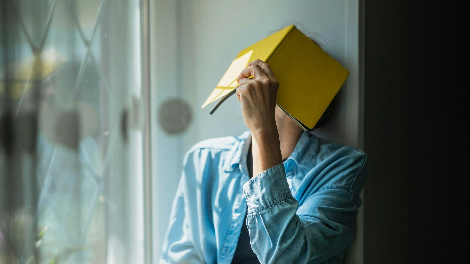 Eine Frau verbirgt ihr Gesicht hinter einem Notizheft