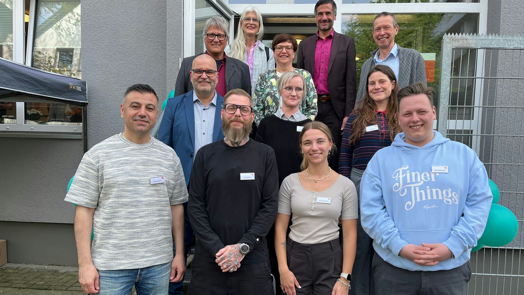 Eine Menschengruppe steht auf den Stufen vor dem Eingang zu einer Suchtberatungsstelle.