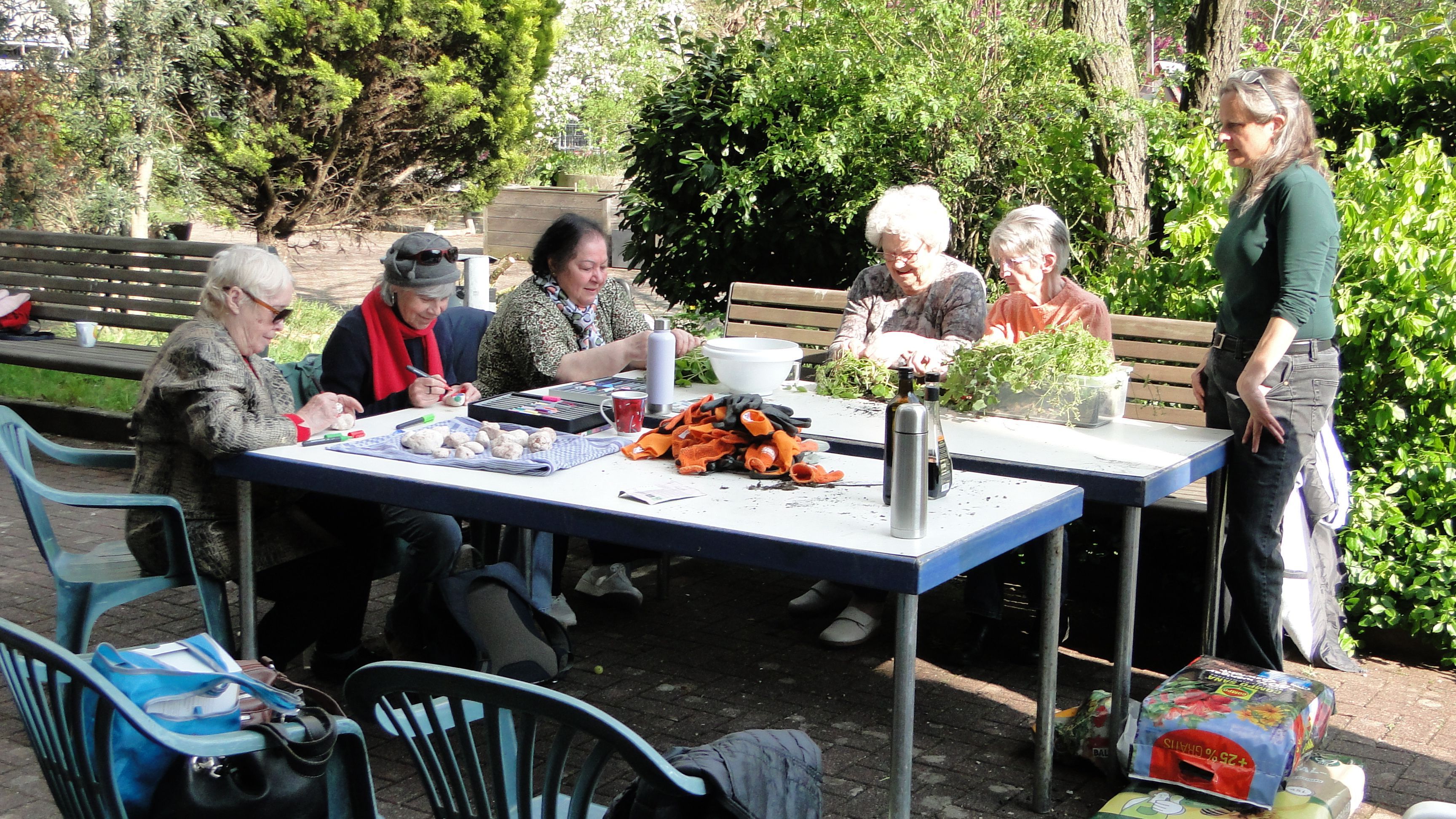 Eine Gruppe Senioren an einem Tisch bei Gartenarbeit. Nicolin Gabrysch (rechts) übernimmt die Leitung des Gartenprojekts.