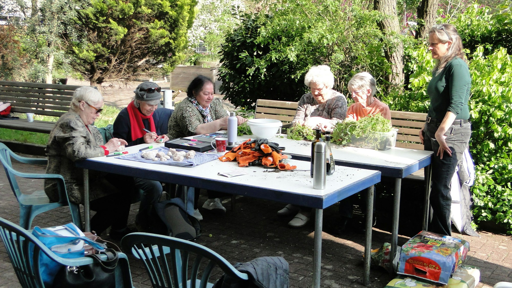 Eine Gruppe Senioren an einem Tisch bei Gartenarbeit. Nicolin Gabrysch (rechts) übernimmt die Leitung des Gartenprojekts.