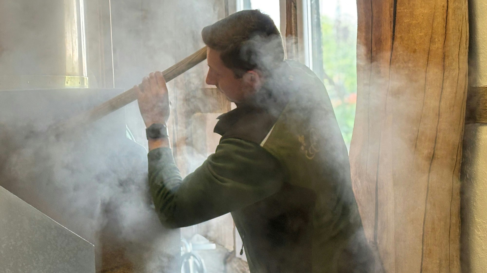 Max Päffgen schippt Treber mit einer Schaufel während er von Dampfschwaden umgeben ist.