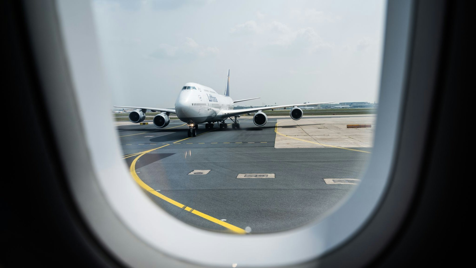 Blick aus einem Flugzeug auf die Rollbahn am Flughafen