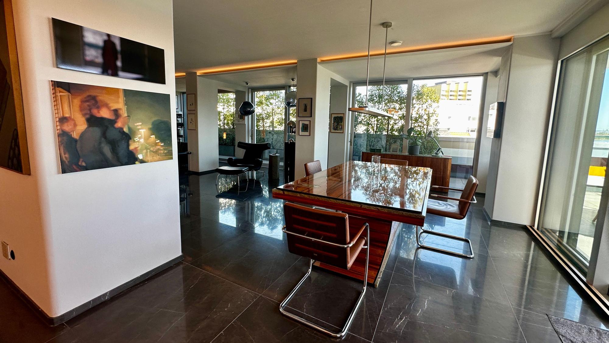 Blick in ein großzügiges offenes Wohnesszimmer mit einem großen blank polierten Tisch.