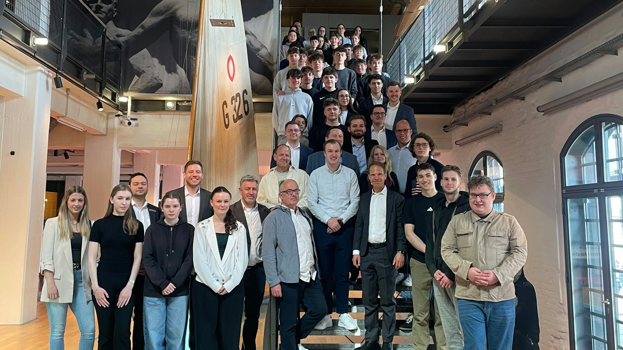 Männer und Frauen stehen vor und auf einer Treppe in einem Gebäude.