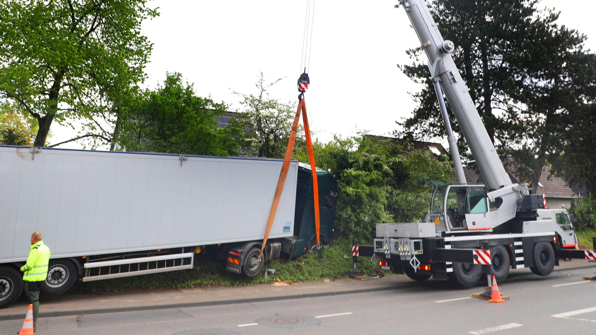 Ein Autokran hebt einen Sattelzug aus einer Böschung.