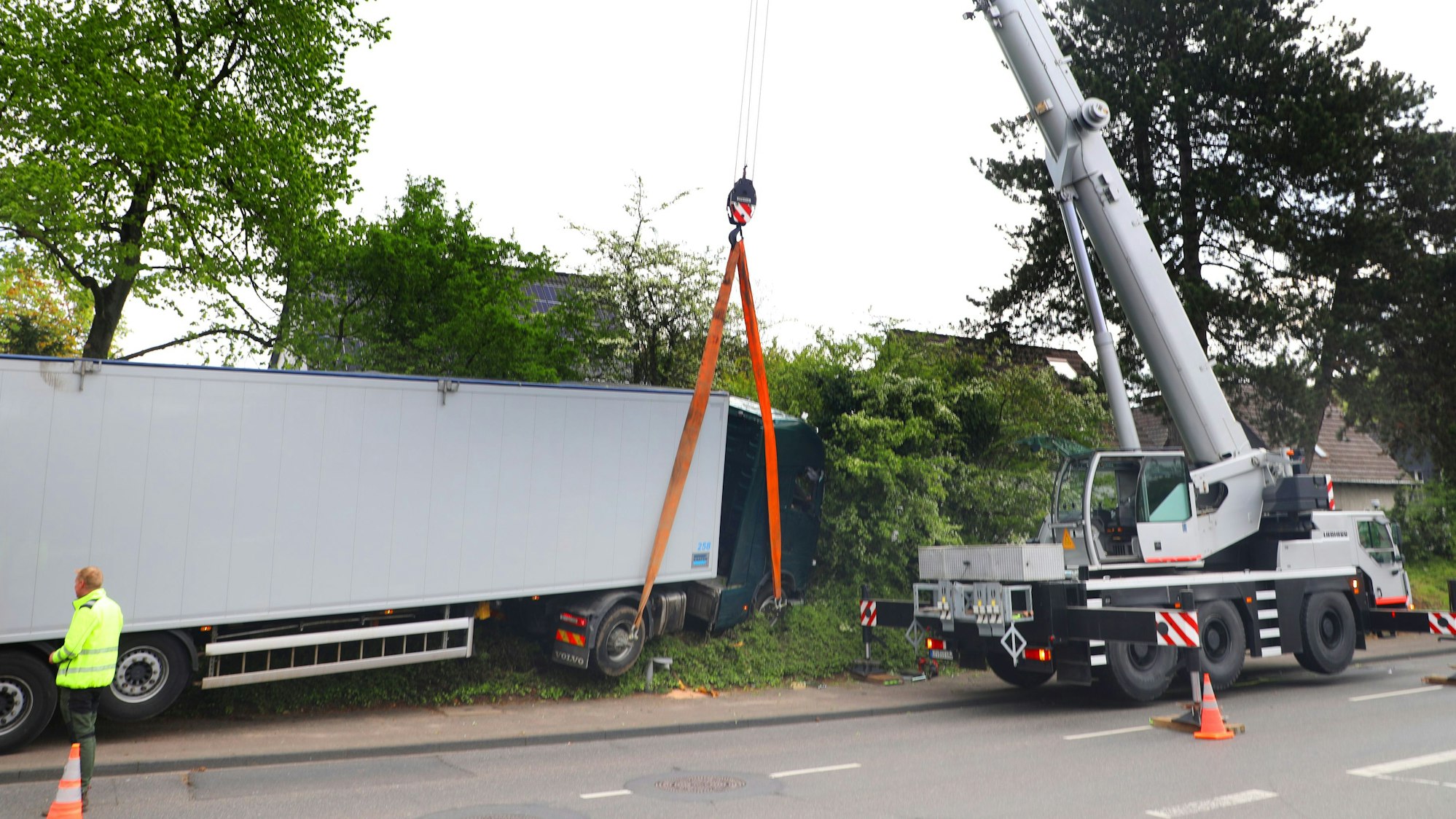 Ein Autokran hebt einen Sattelzug aus einer Böschung.