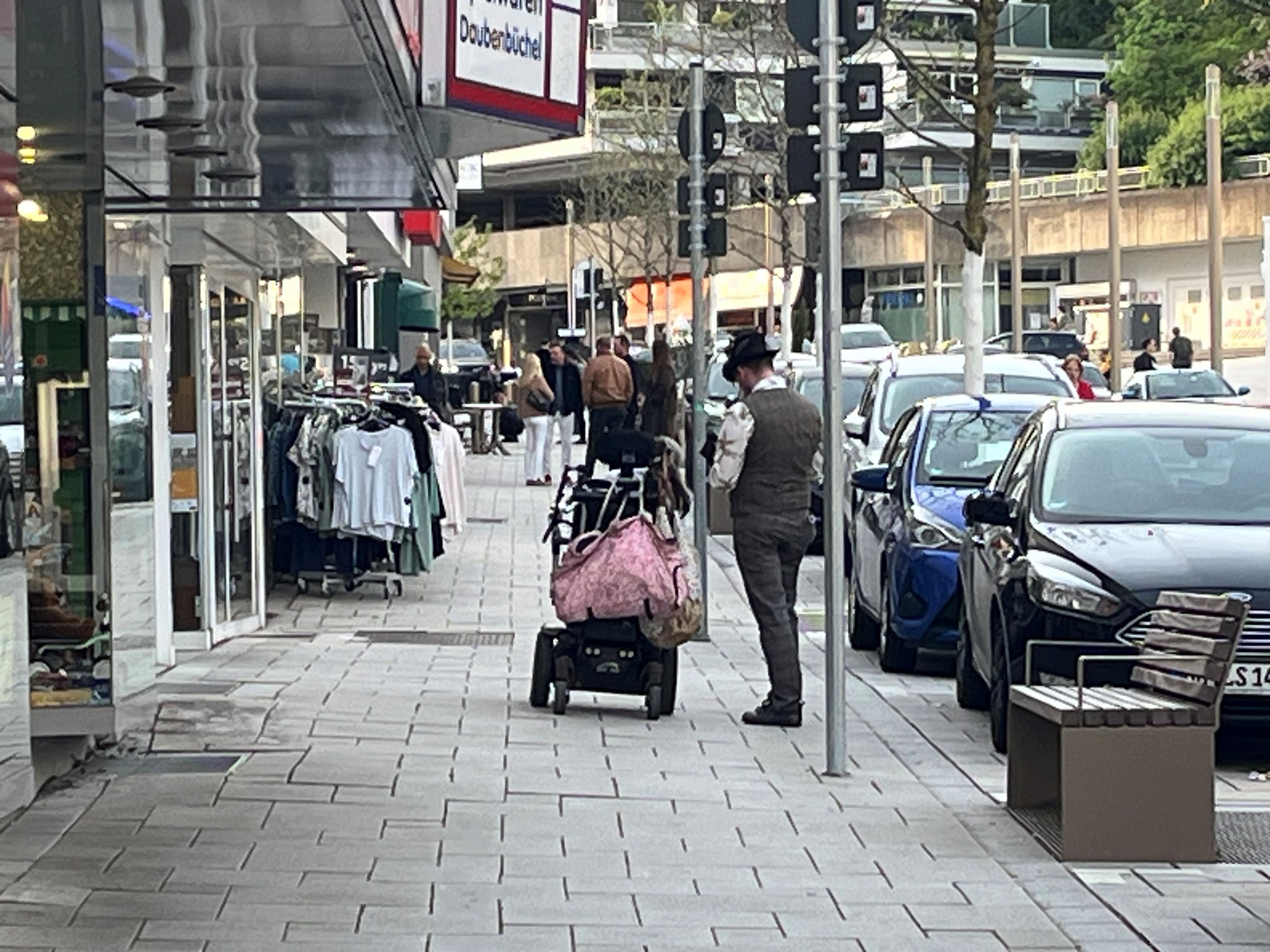 Ein Mann steht neben einem Rollstuhl vor einem Schaufenster.