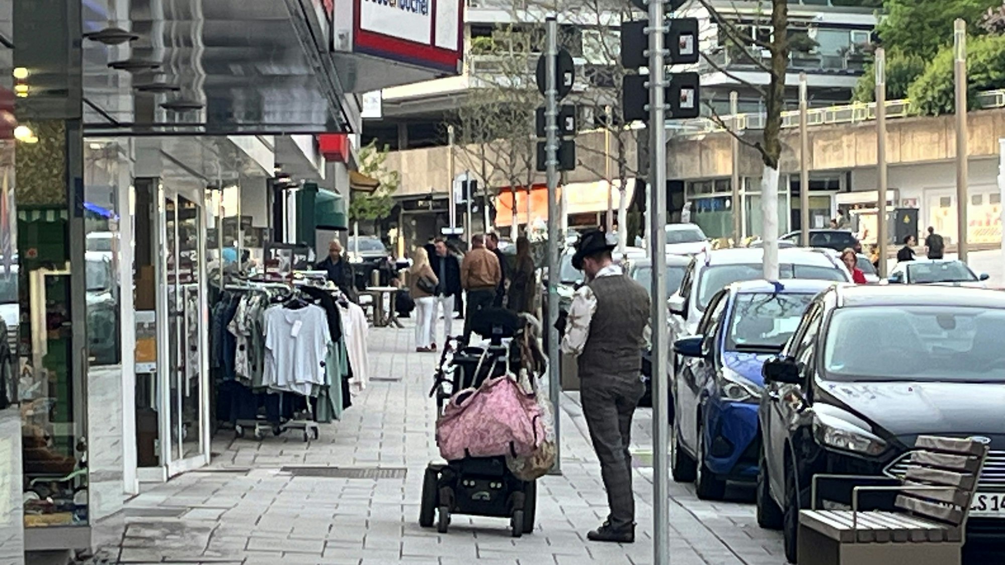 Ein Mann steht neben einem Rollstuhl vor einem Schaufenster.