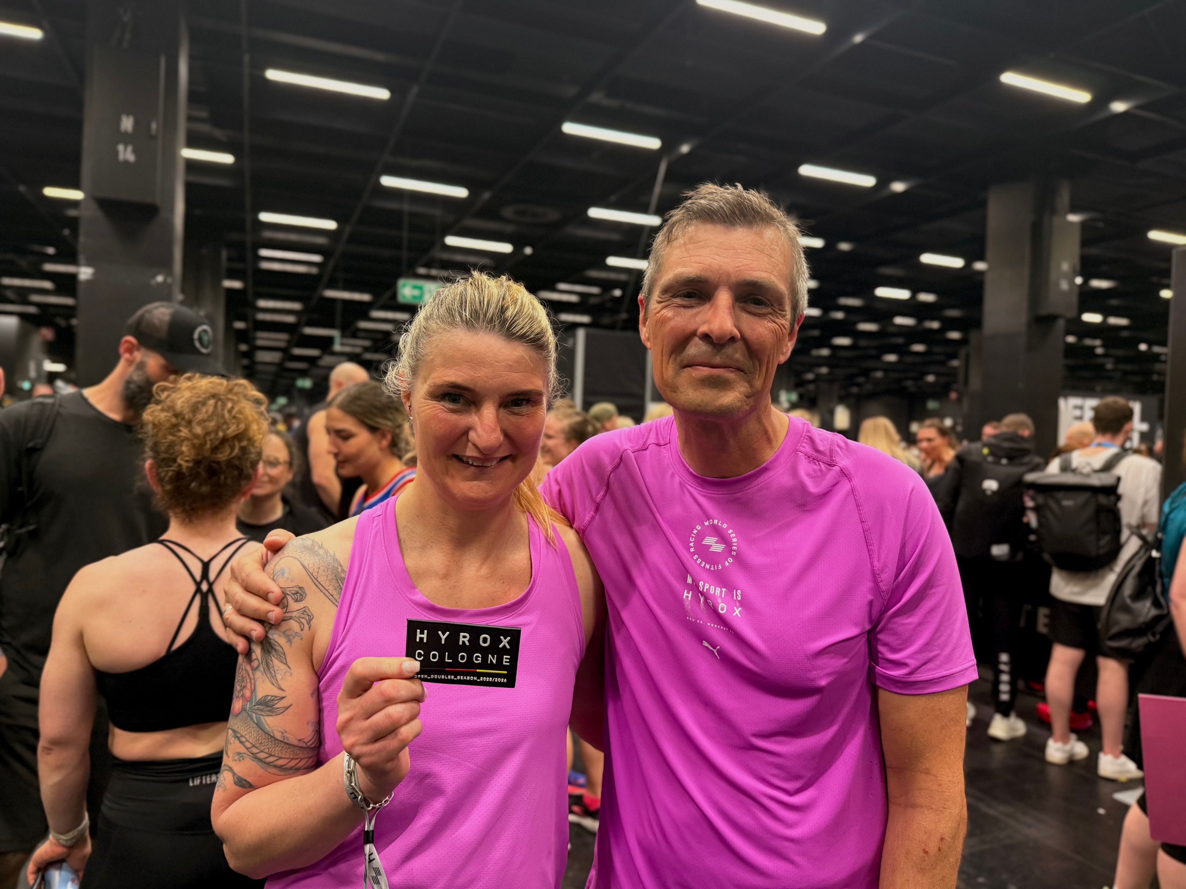 Manuela Petruk und Stefan Kauhardt, beide im pinken Sportdress, im Zielbereich des Hyrox in Köln