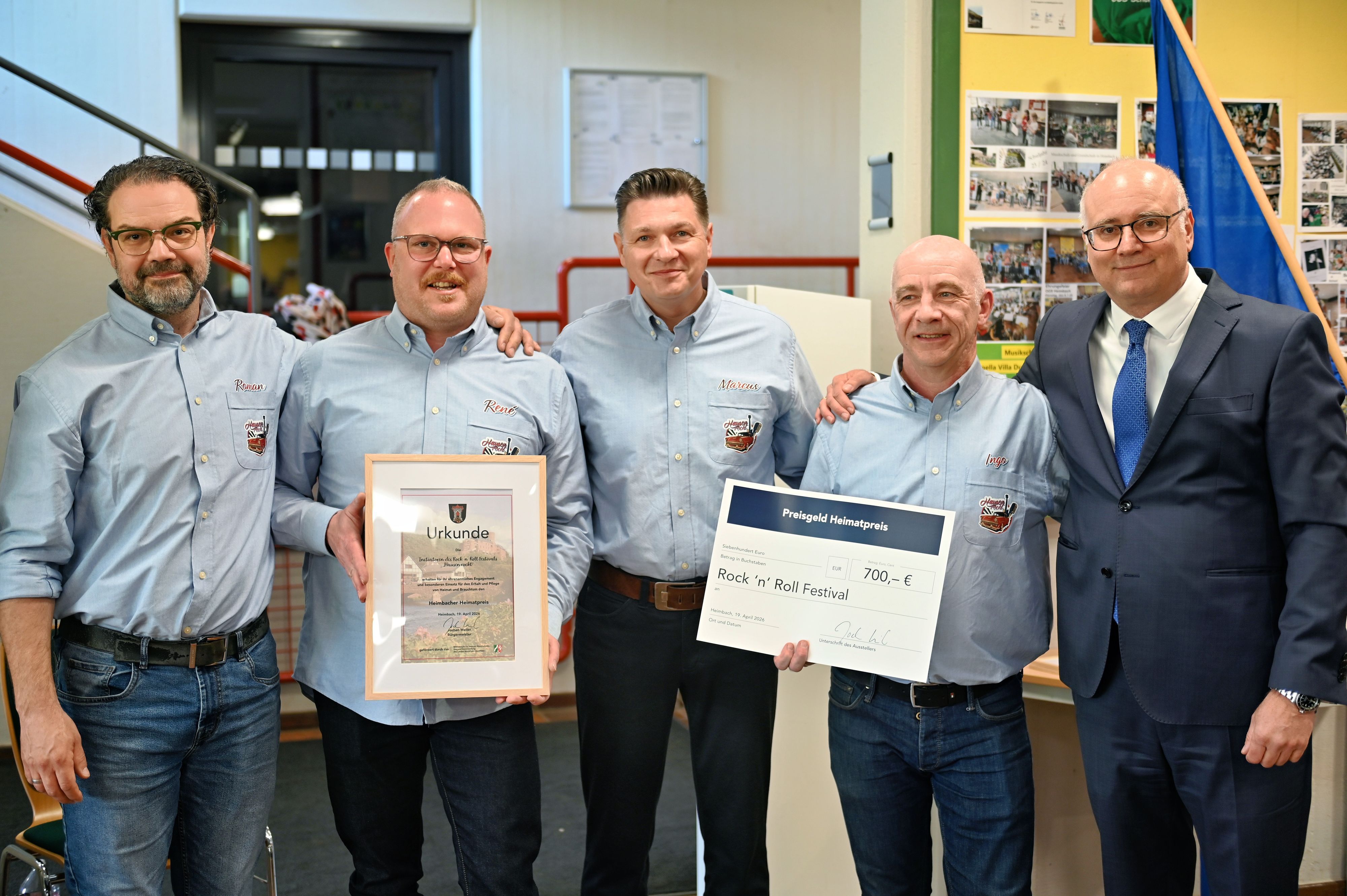 Die vier Geehrten stehen nebeneinander und tragen blaue Hemden.