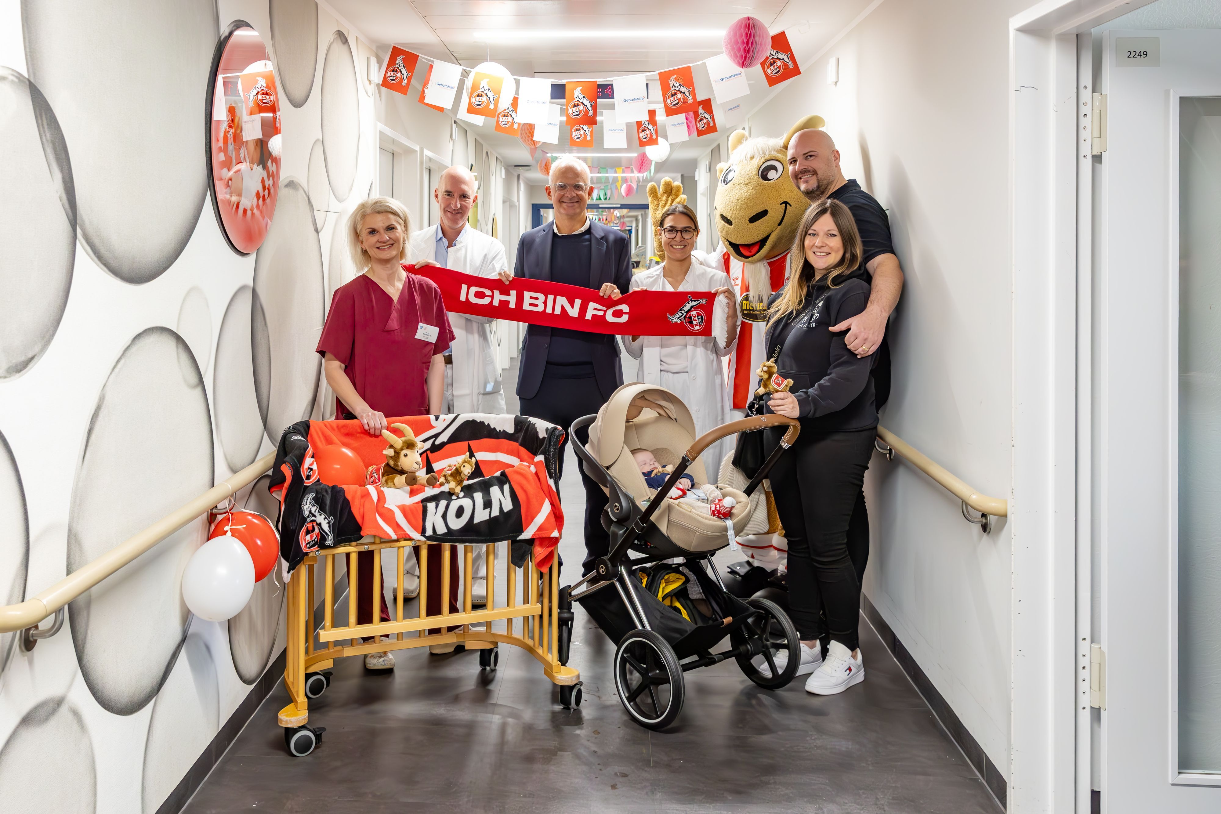 Monique Nentwich, Daniel Rein, Jörg Alvermann, Ärztin Yaya van der Goltz, der Plüsch-Hennes und die Familie Romic feiern den elften Geburtstag des FC-Zimmers.