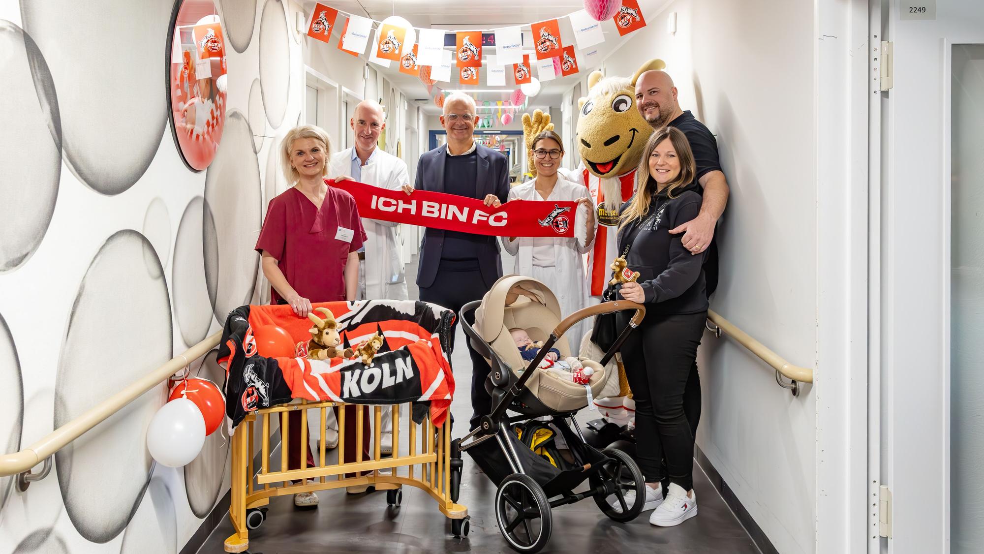 Monique Nentwich, Daniel Rein, Jörg Alvermann, Ärztin Yaya van der Goltz, der Plüsch-Hennes und die Familie Romic feiern den elften Geburtstag des FC-Zimmers.