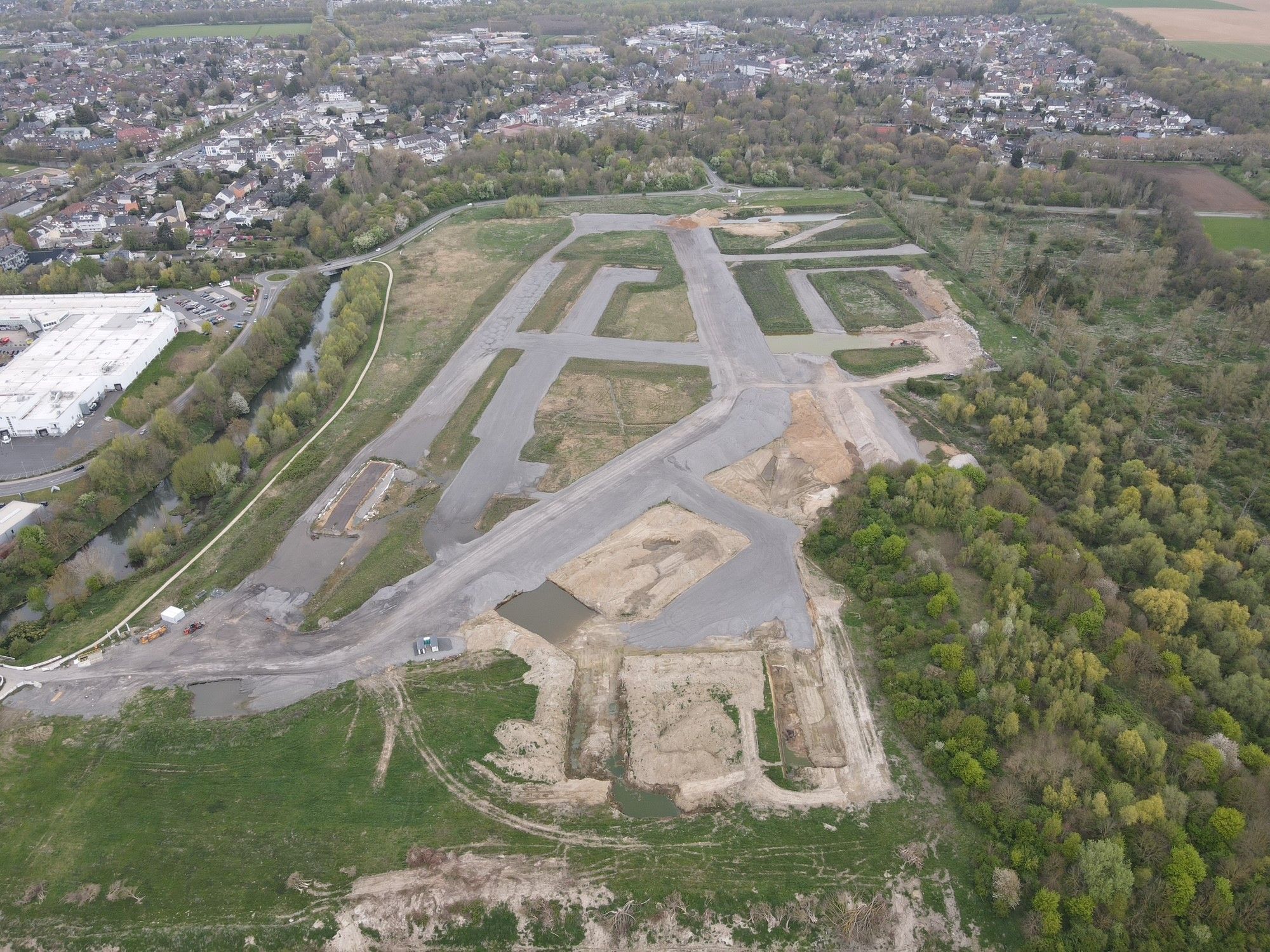 Zu sehen ist ein Luftbild, das graue Aschehalden in einem geplanten Neubaugebiet zeigt.