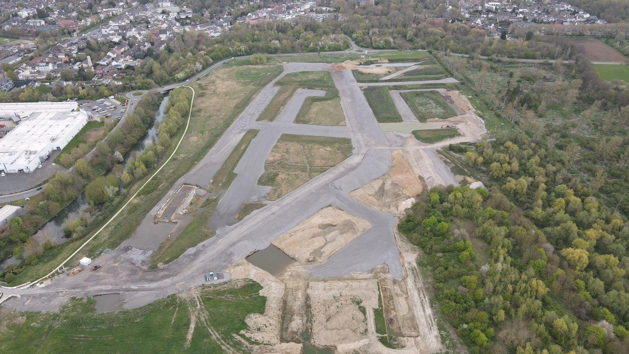 Zu sehen ist ein Luftbild, das graue Aschehalden in einem geplanten Neubaugebiet zeigt.
