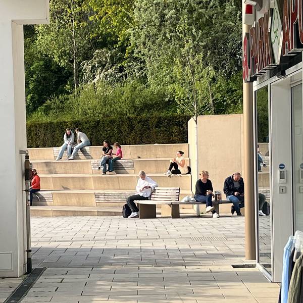 Menschen sitzen zu zweit oder zu dritt auf den Stufen.