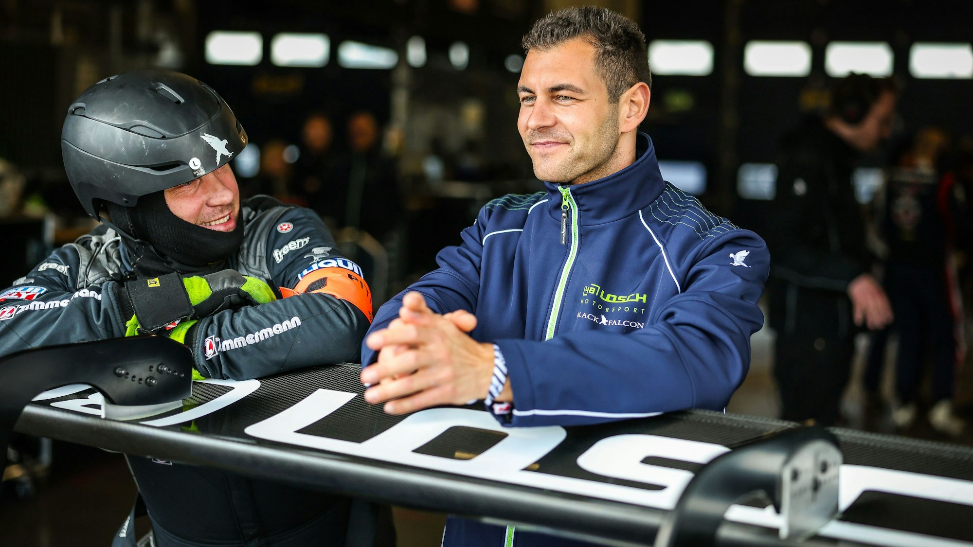 Tobias Müller lehnt sich auf einen Spoiler und unterhält sich mit einem Mechaniker.