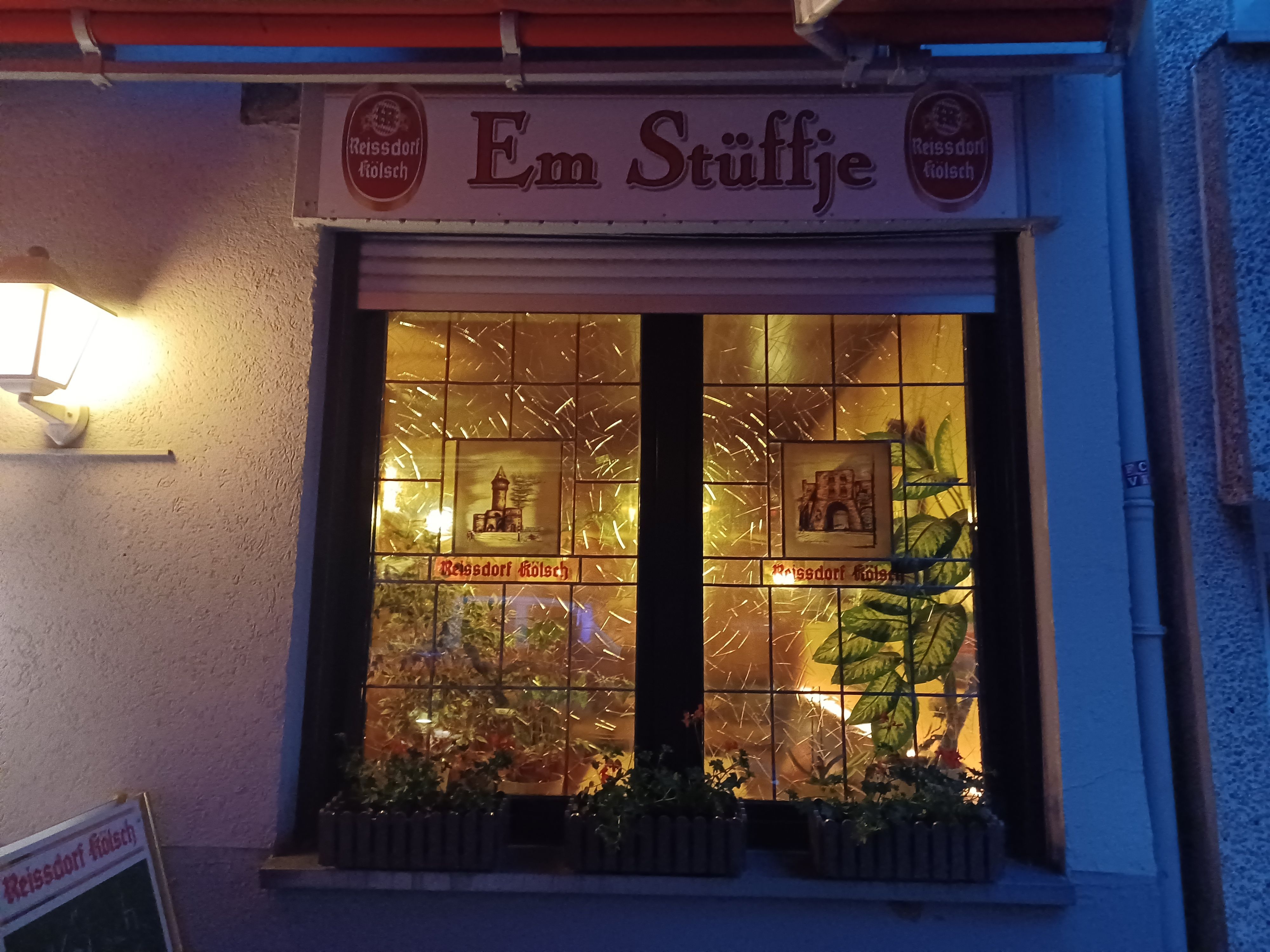 Zu sehen sind die bunten Fensterscheiben einer Eckkneipe.