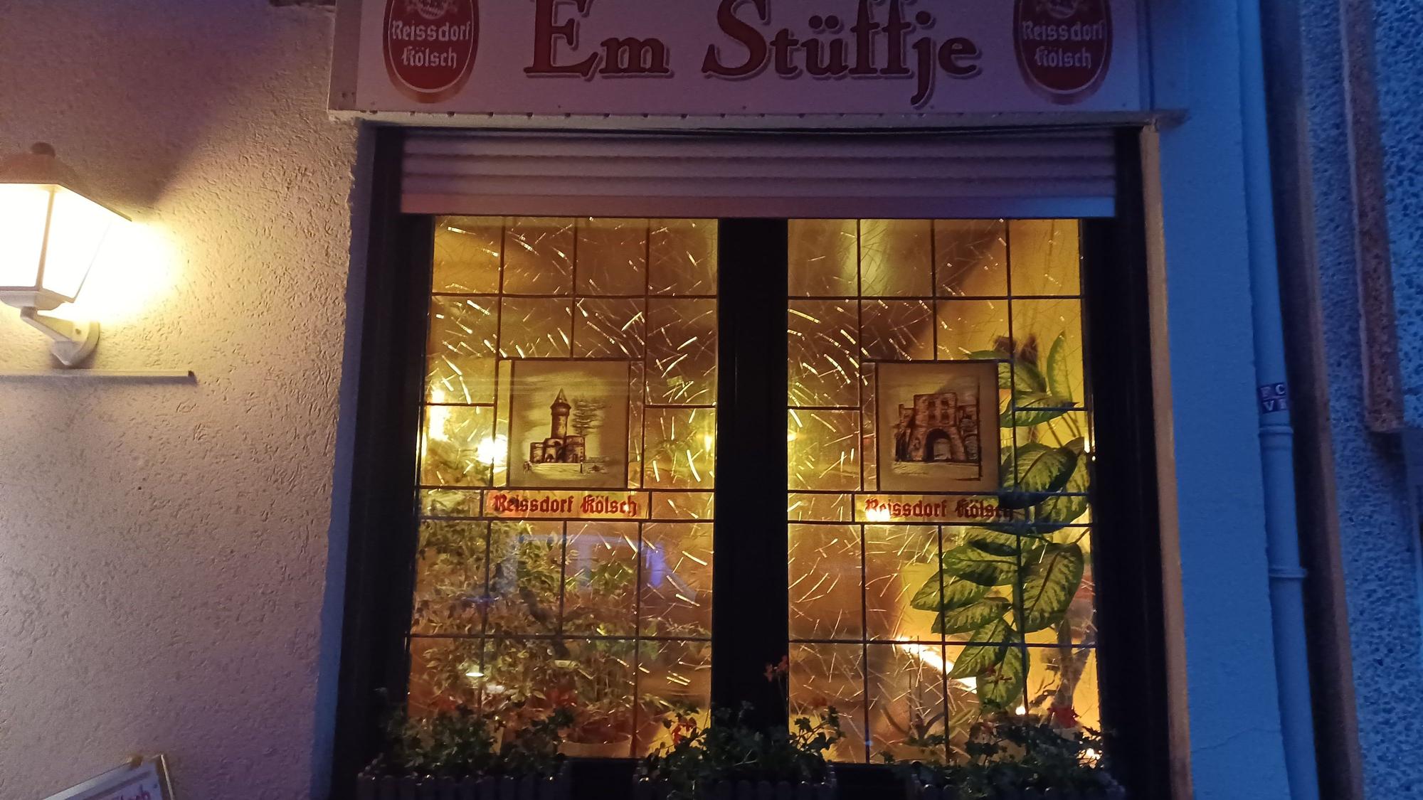 Zu sehen sind die bunten Fensterscheiben einer Eckkneipe.