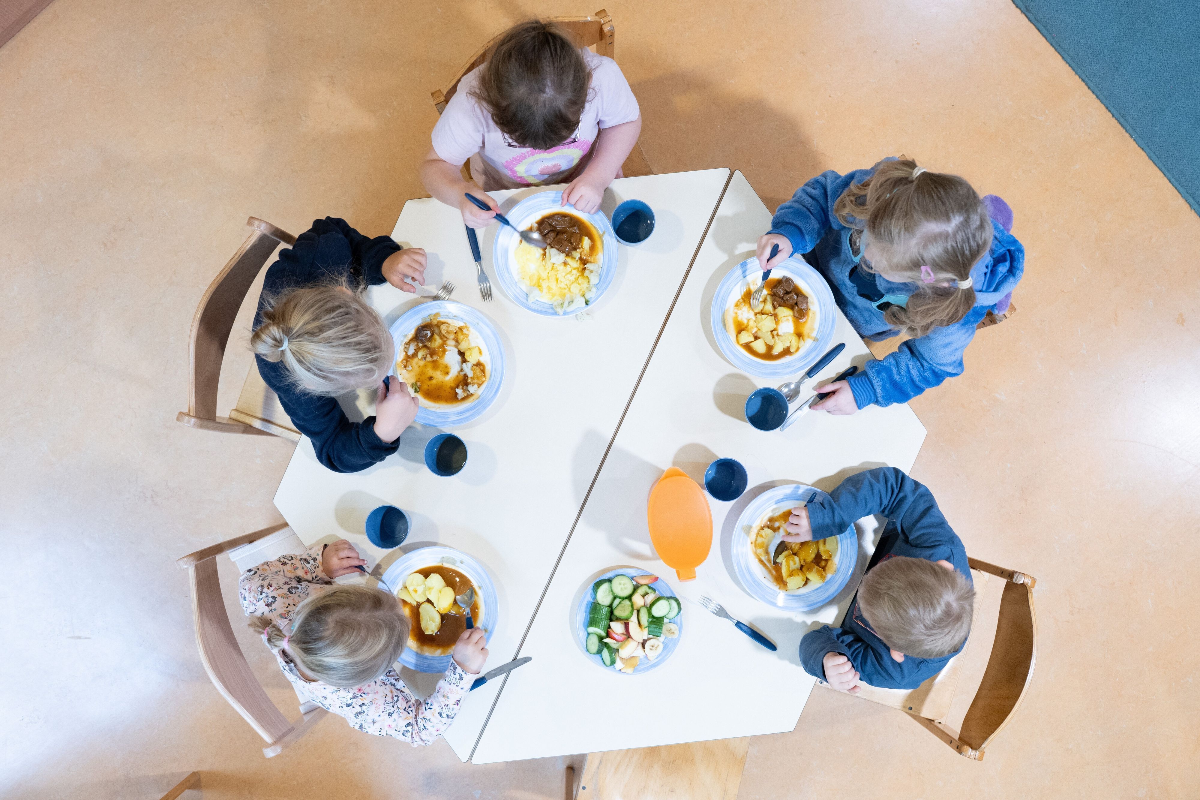 Kinder sitzenin einer Kindertagesstätte beim Mittagessen an einem Tisch. (Symbolbild)
