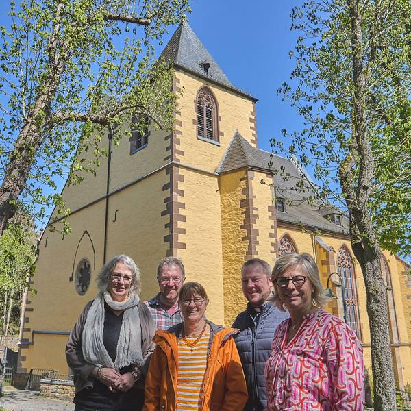 Das neue Leitungsteam des Pastoralen Raumes Hellenthal/Schleiden steht vor einer Kirche.