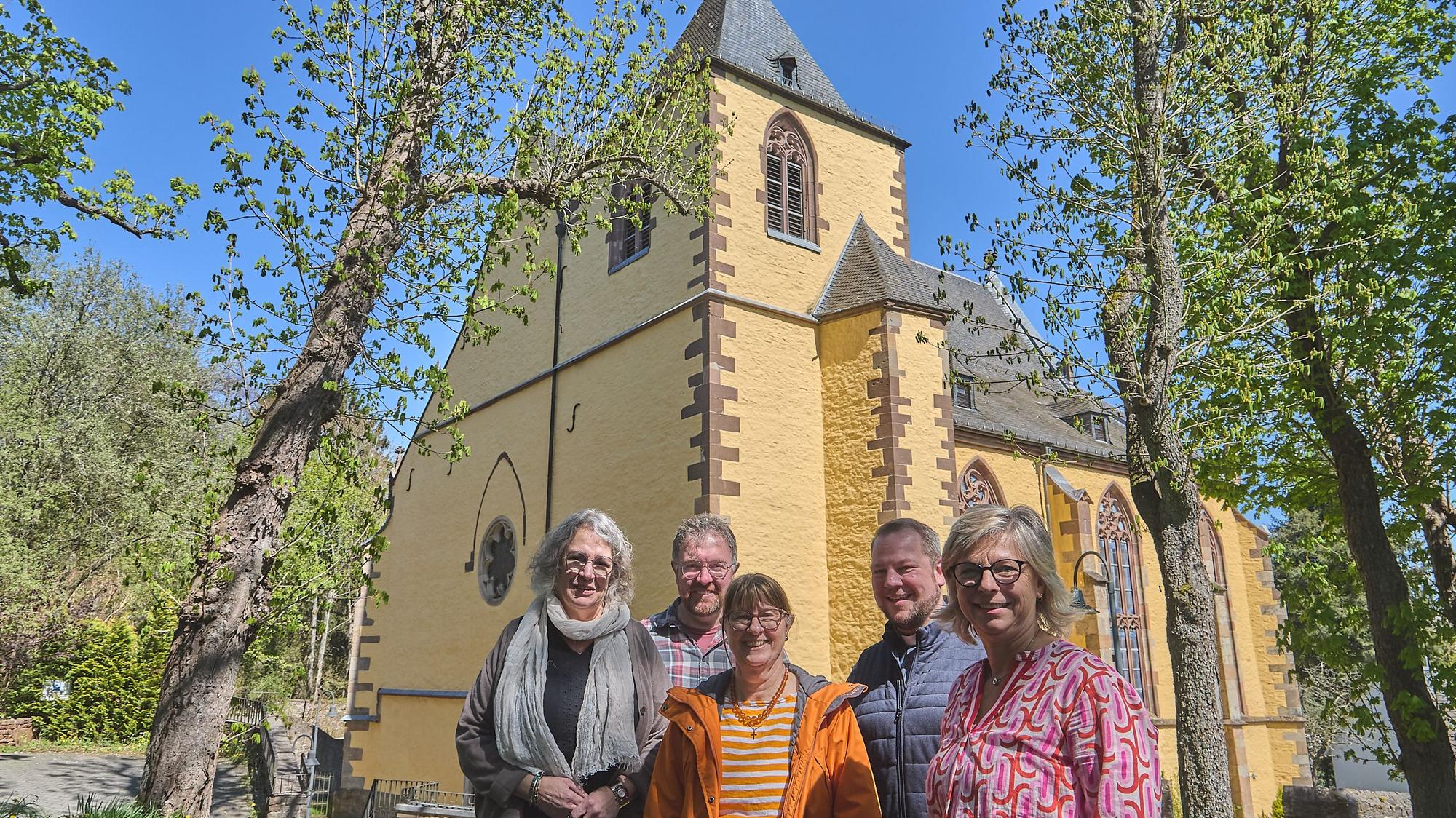 Das neue Leitungsteam des Pastoralen Raumes Hellenthal/Schleiden steht vor einer Kirche.