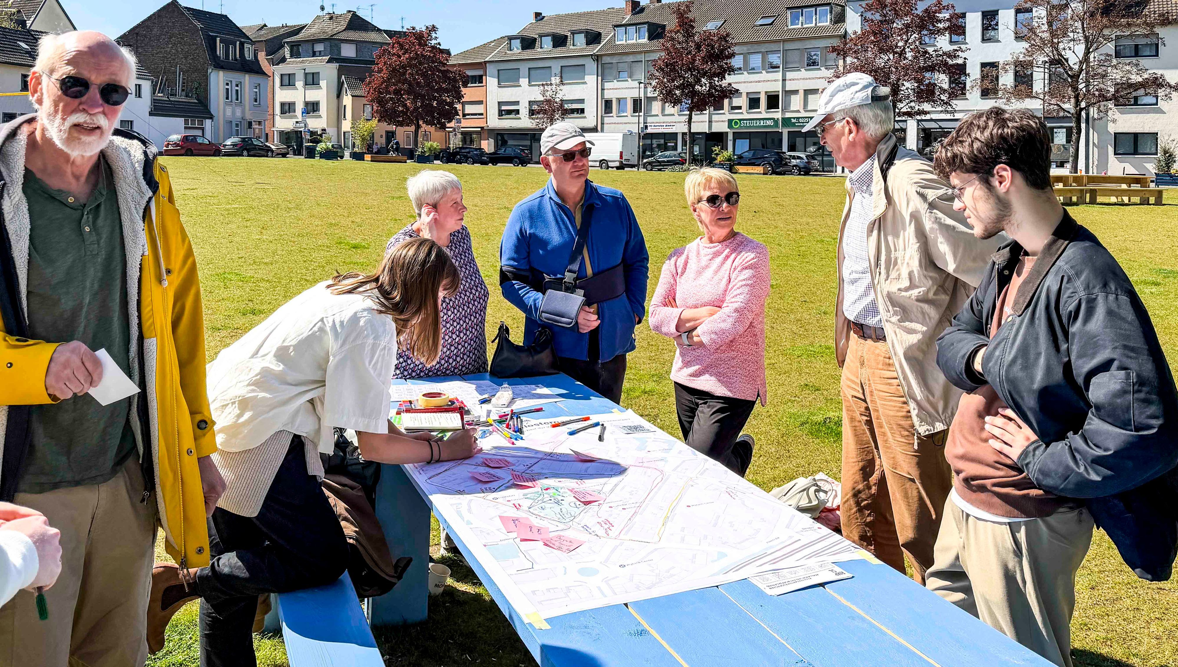 Das Bild zeigt einige Senioren, die um einen Tisch herumstehen und Ideen sammeln.