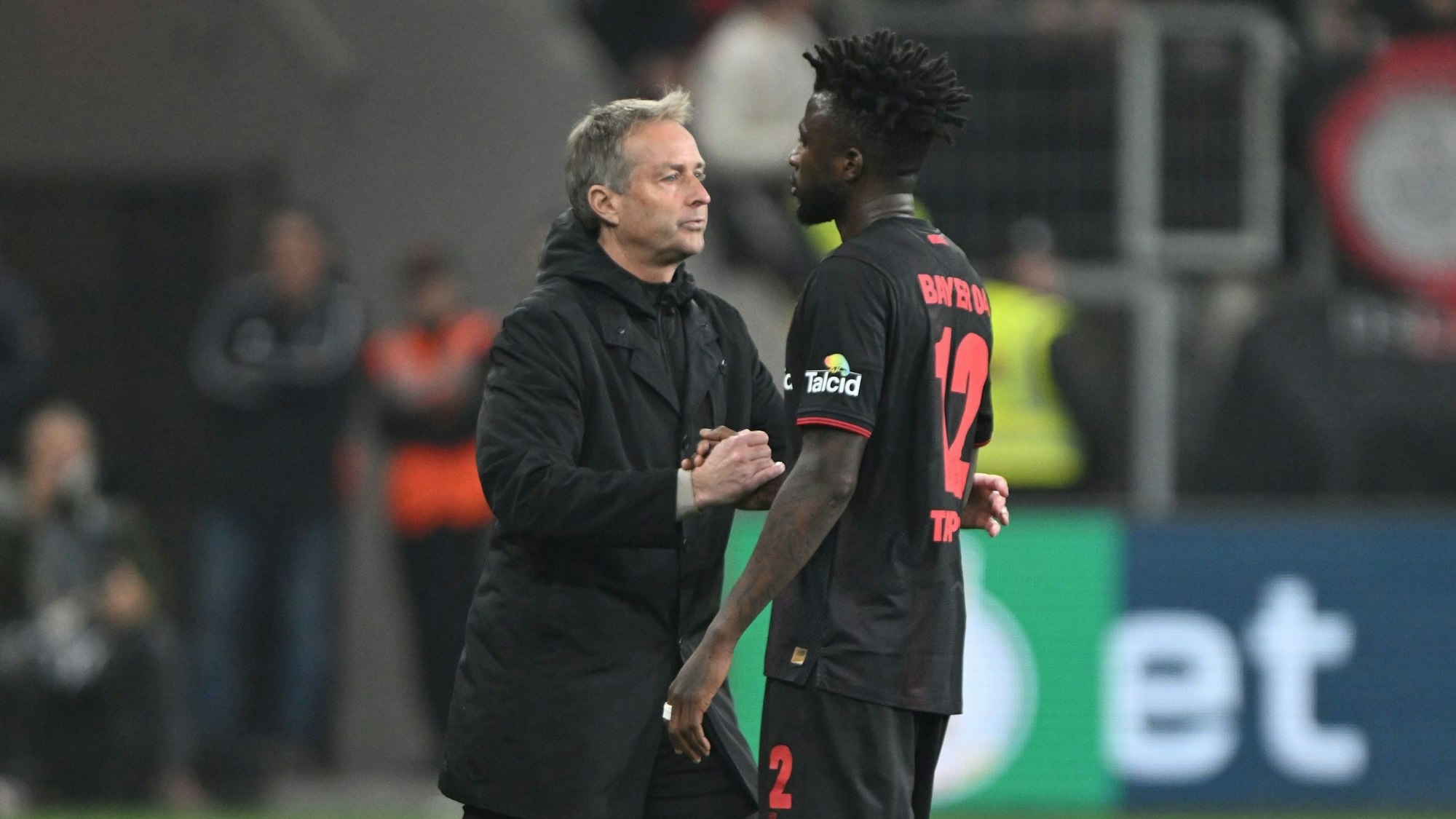 22.04.2026, Nordrhein-Westfalen, Leverkusen: Fußball, Männer: DFB-Pokal, Bayer Leverkusen - Bayern München, Halbfinale, BayArena, Trainer Kasper Hjulmand (Bayer Leverkusen) und Edmond Tapsoba (Bayer Leverkusen) schütteln sich nach der Partie die Hand. WICHTIGER HINWEIS: Gemäß den Vorgaben der DFL Deutsche Fußball Liga bzw. des DFB Deutscher Fußball-Bund ist es untersagt, in dem Stadion und/oder vom Spiel angefertigte Fotoaufnahmen in Form von Sequenzbildern und/oder videoähnlichen Fotostrecken zu verwerten bzw. verwerten zu lassen. Foto: Federico Gambarini/dpa +++ dpa-Bildfunk +++