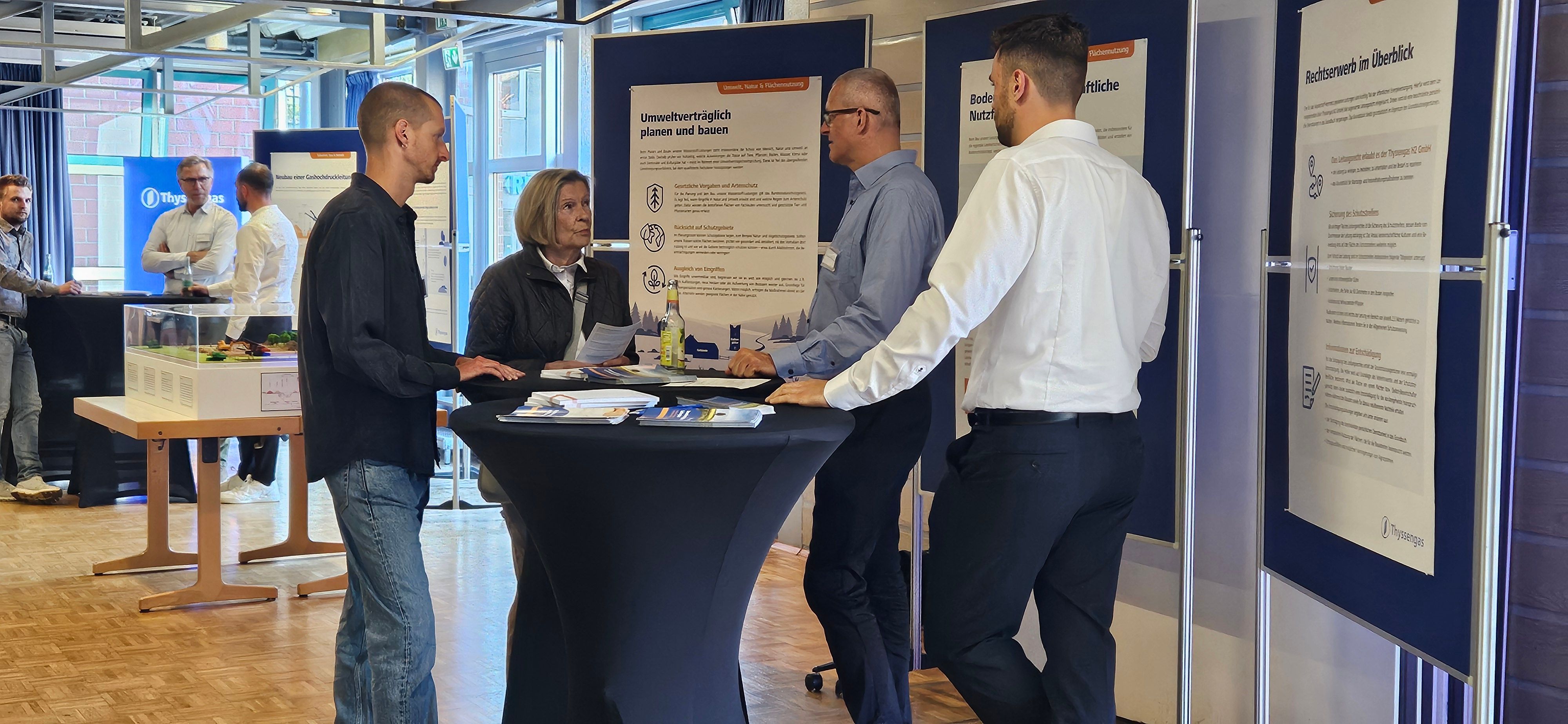 Das Foto zeigt Menschen an einem Stehtisch vor Informationstafeln im Bürgerhaus.