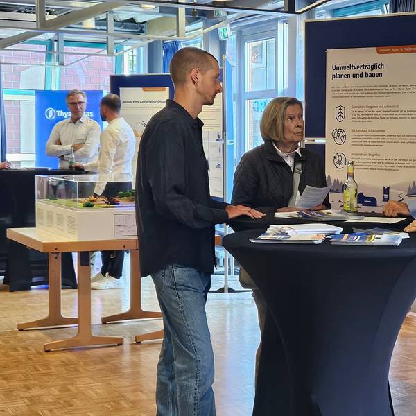 Das Foto zeigt Menschen an einem Stehtisch vor Informationstafeln im Bürgerhaus.