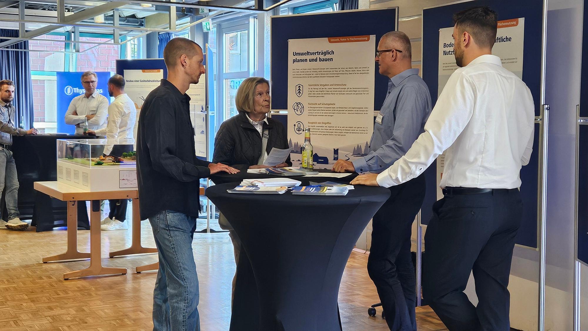 Das Foto zeigt Menschen an einem Stehtisch vor Informationstafeln im Bürgerhaus.