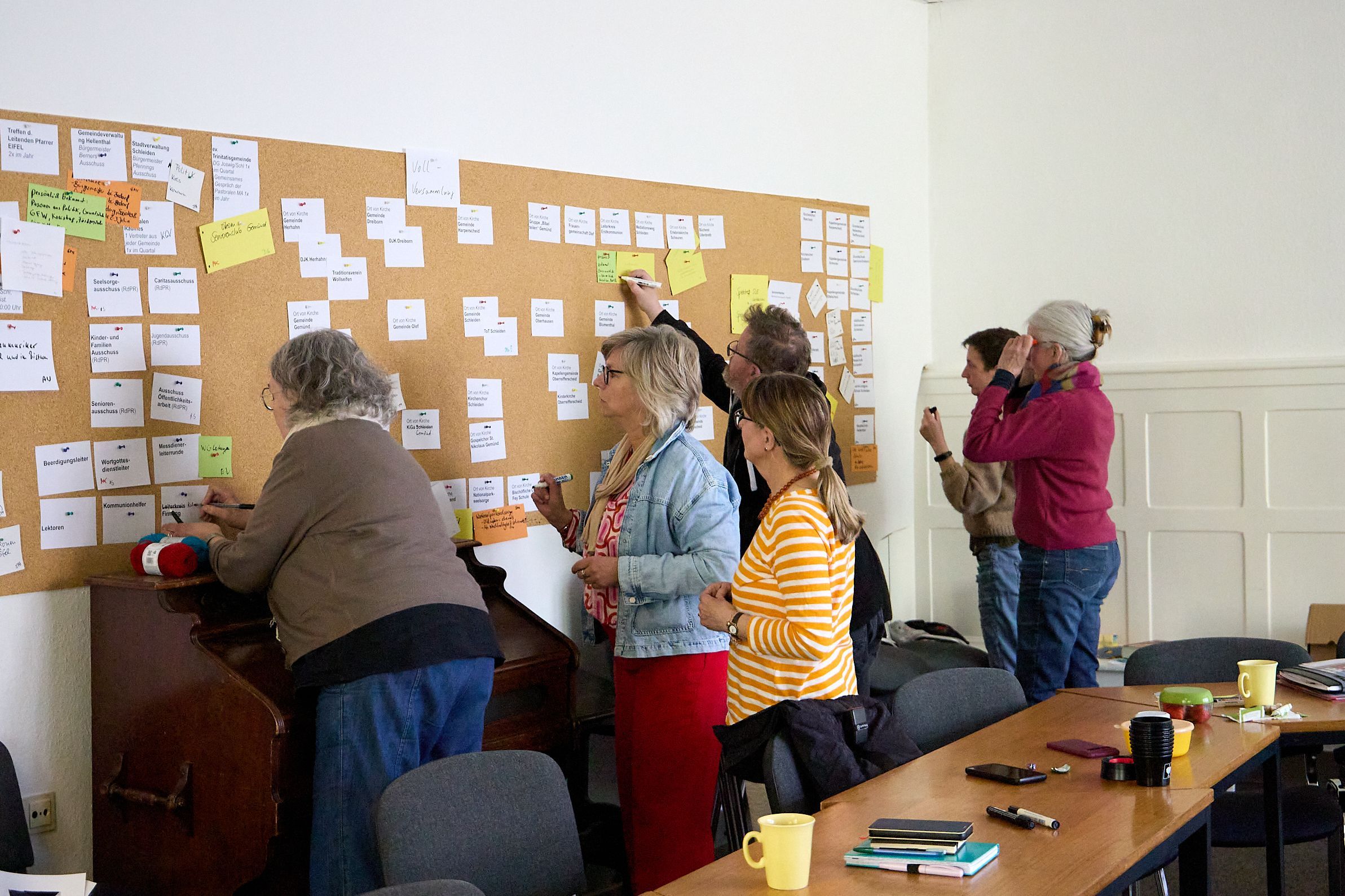 Das Pastoral- und Leitungsteam heftet Zettel an eine Pinnwand und beschreibt das Papier.
