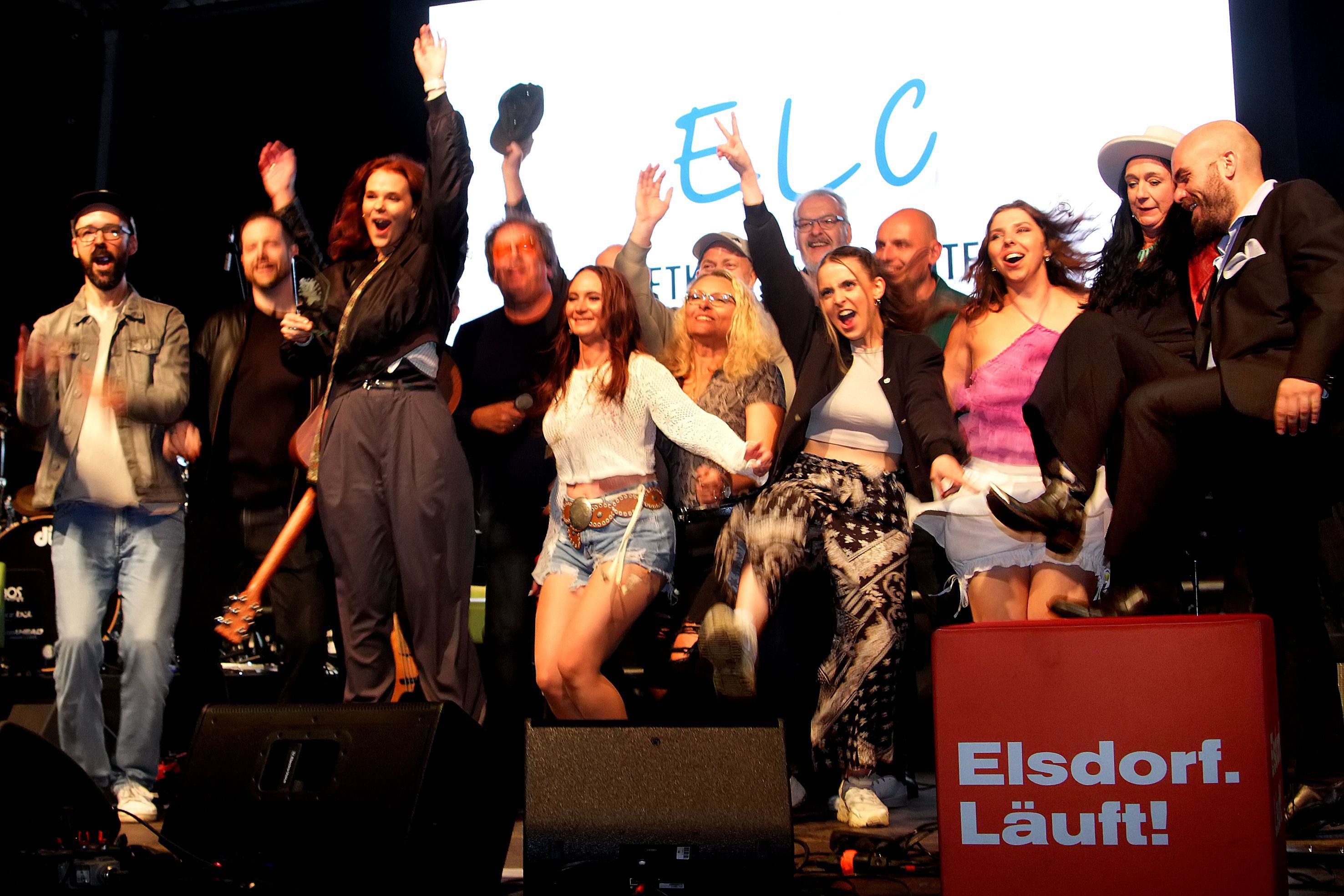 Zu sehen sind gut gelaunte Musiker auf einer Bühne.