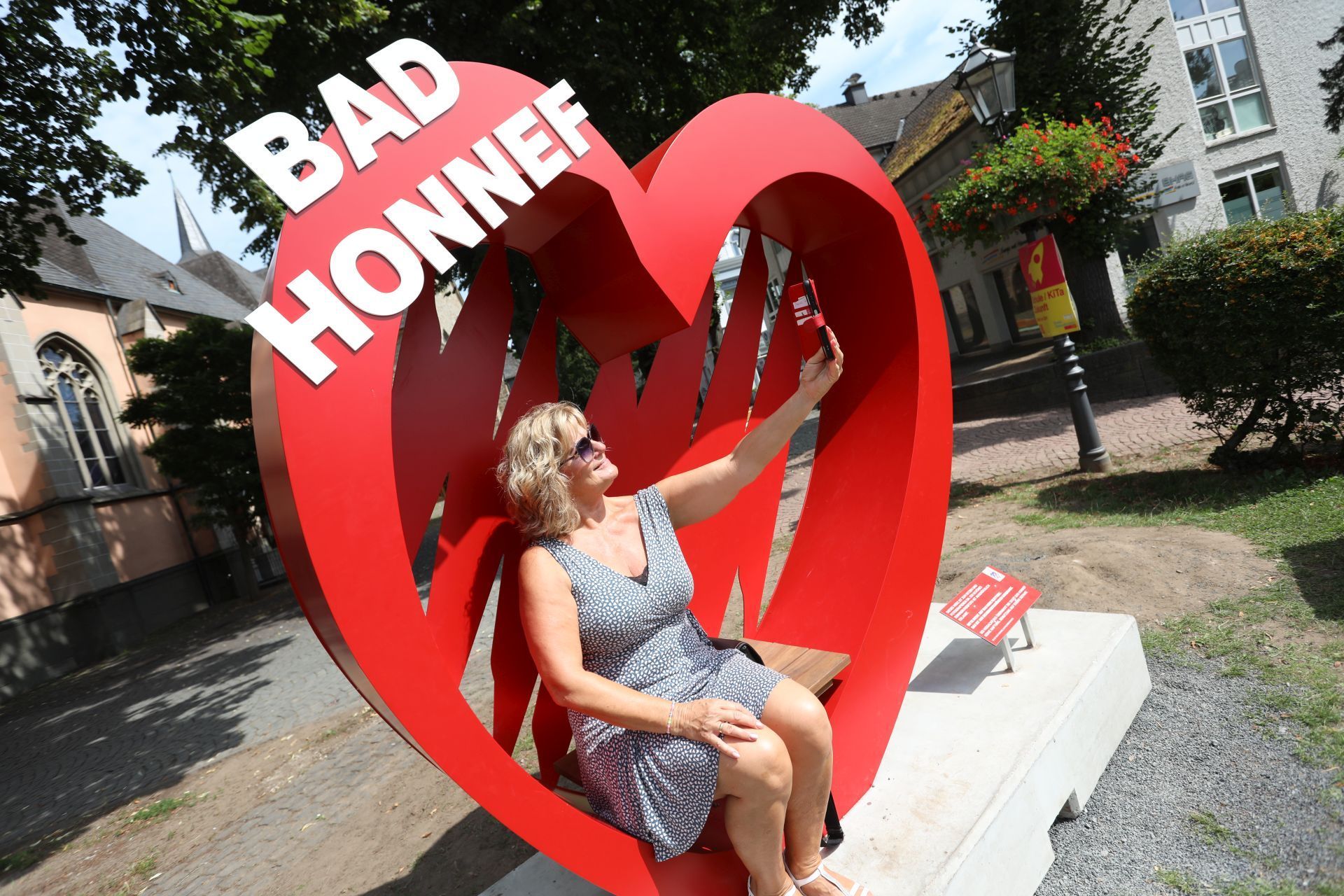 Eine Frau macht ein Selfie in einem Foto-Spot, einem großen roten Herz.