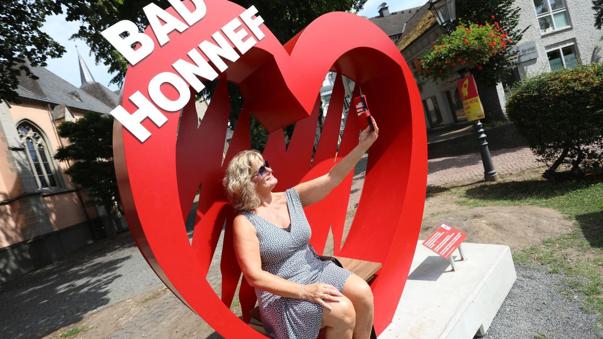 Eine Frau macht ein Selfie in einem Foto-Spot, einem großen roten Herz.