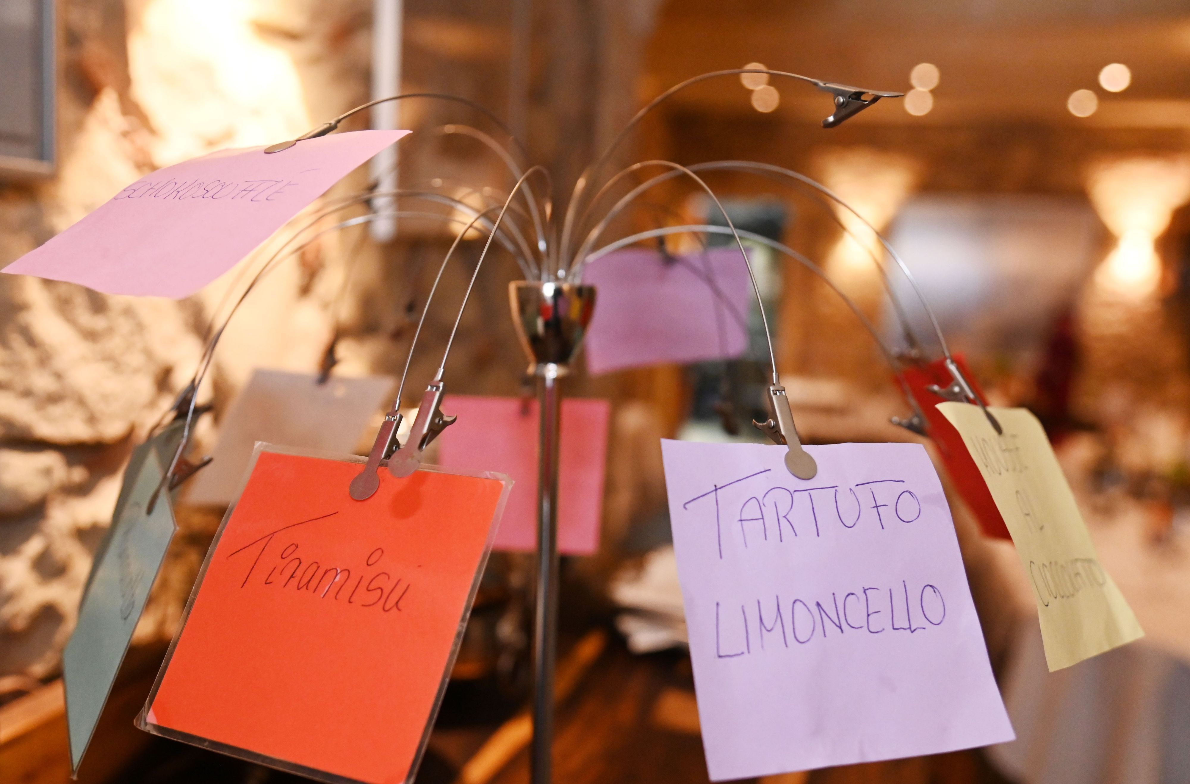 Eine Haltevorrichtung mit Clips, an der Zettel mit den Desserts auf buntem Papier hängen.