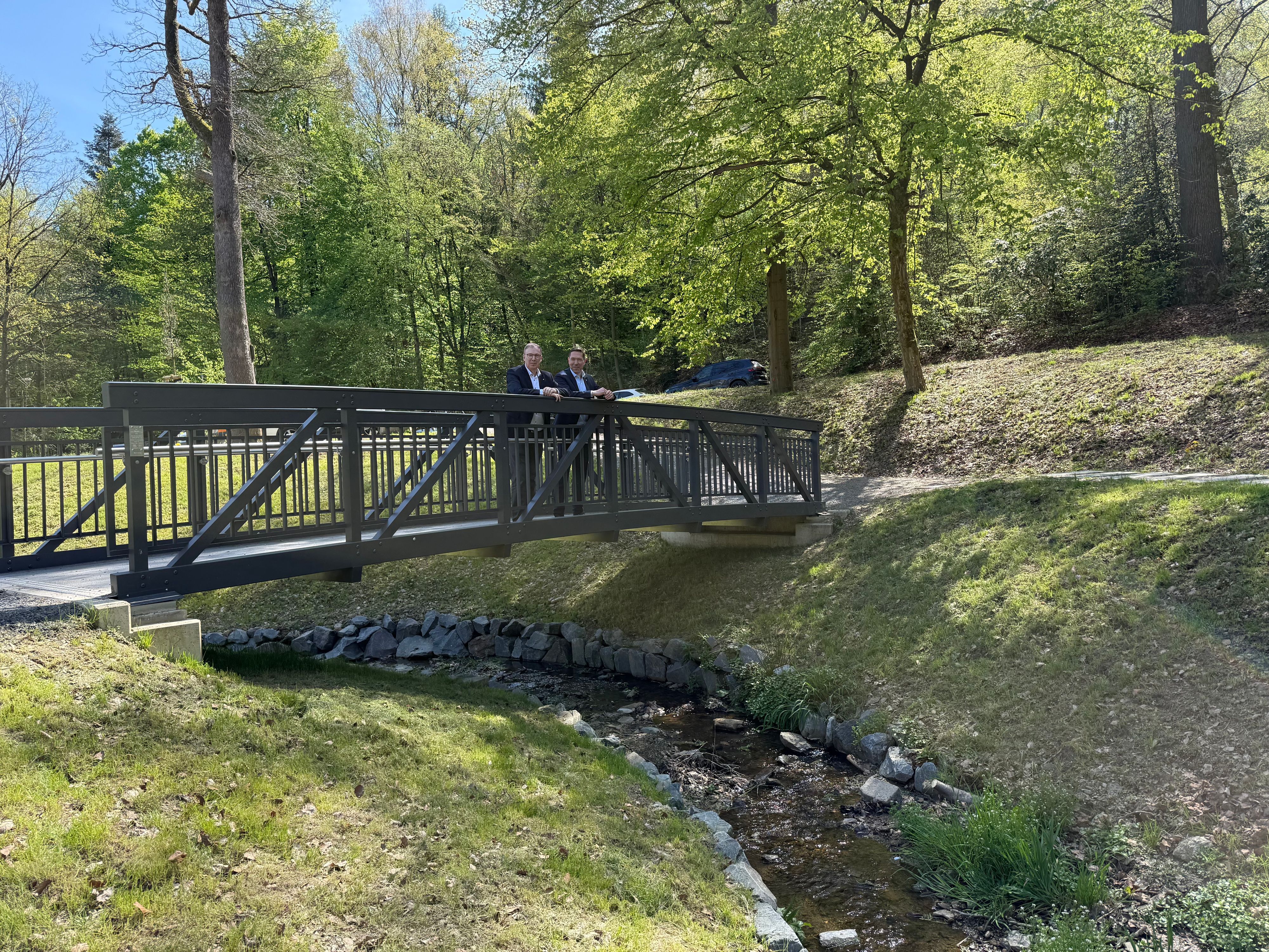 Raoul Halding-Hoppenheit und Hefner stehen auf der neuen Brücke im Hömicker Bachgarten.