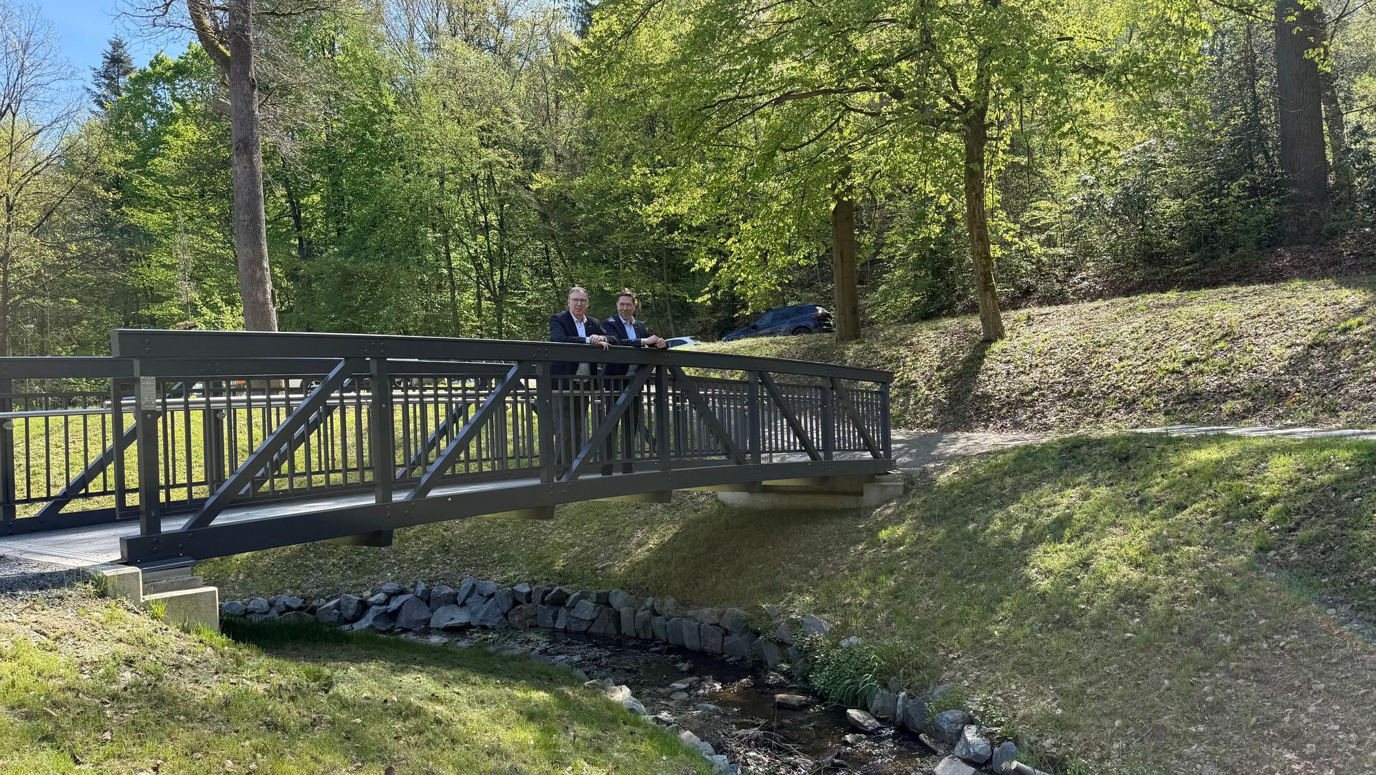 Raoul Halding-Hoppenheit und Hefner stehen auf der neuen Brücke im Hömicker Bachgarten.