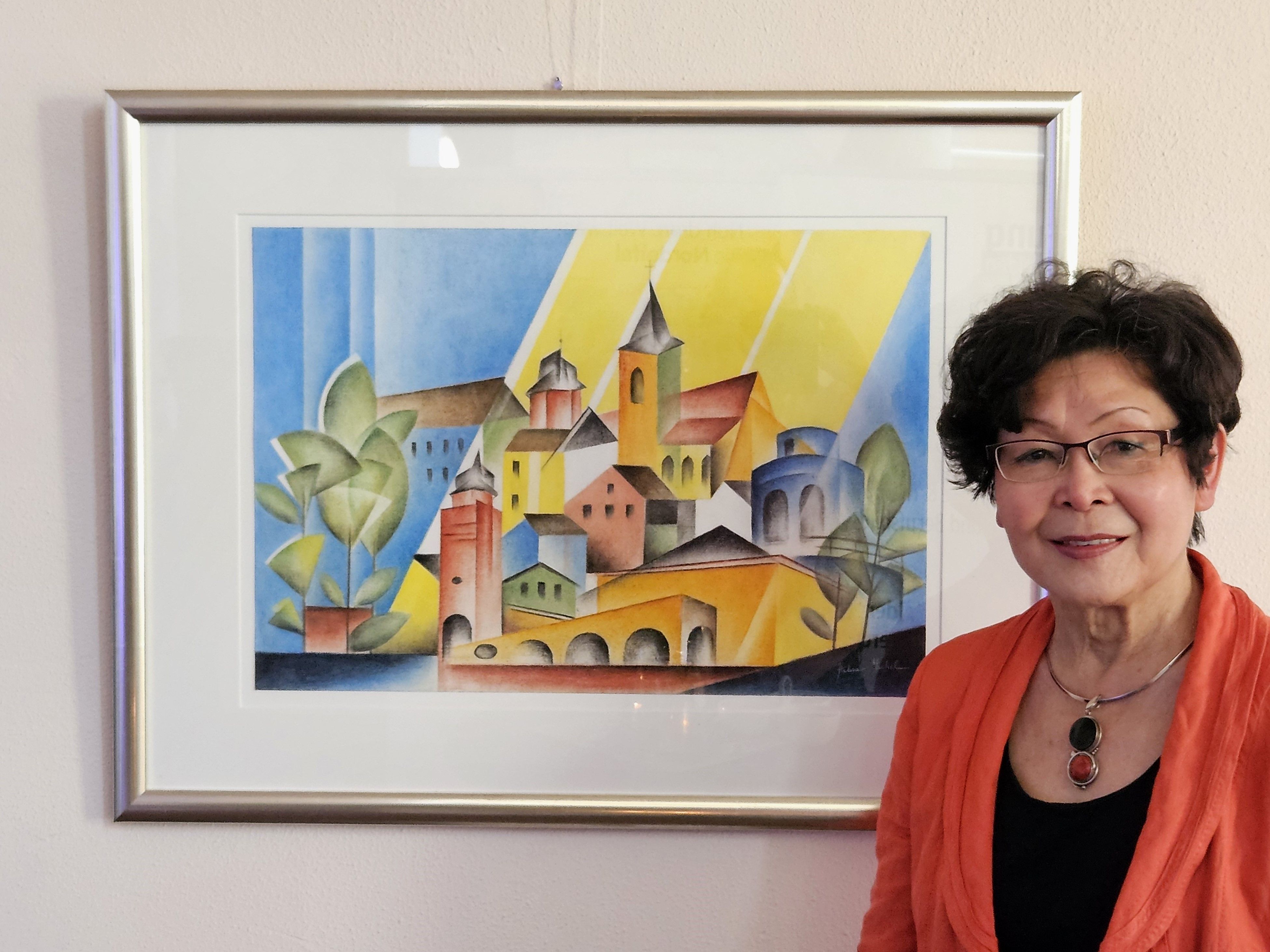 Die Künstlerin steht neben ihrem Bild.