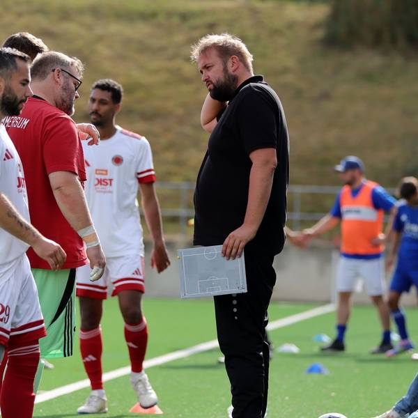 Sebastian Reisenauer steht am Spielfeldrand, In der Hand hält er eine kleine Taktiktafel.