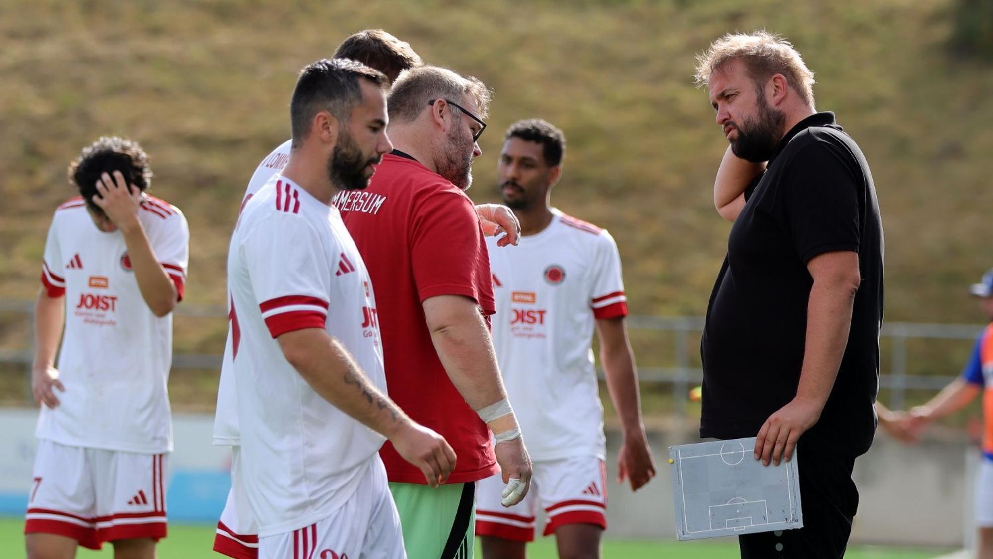 Sebastian Reisenauer steht am Spielfeldrand, In der Hand hält er eine kleine Taktiktafel.